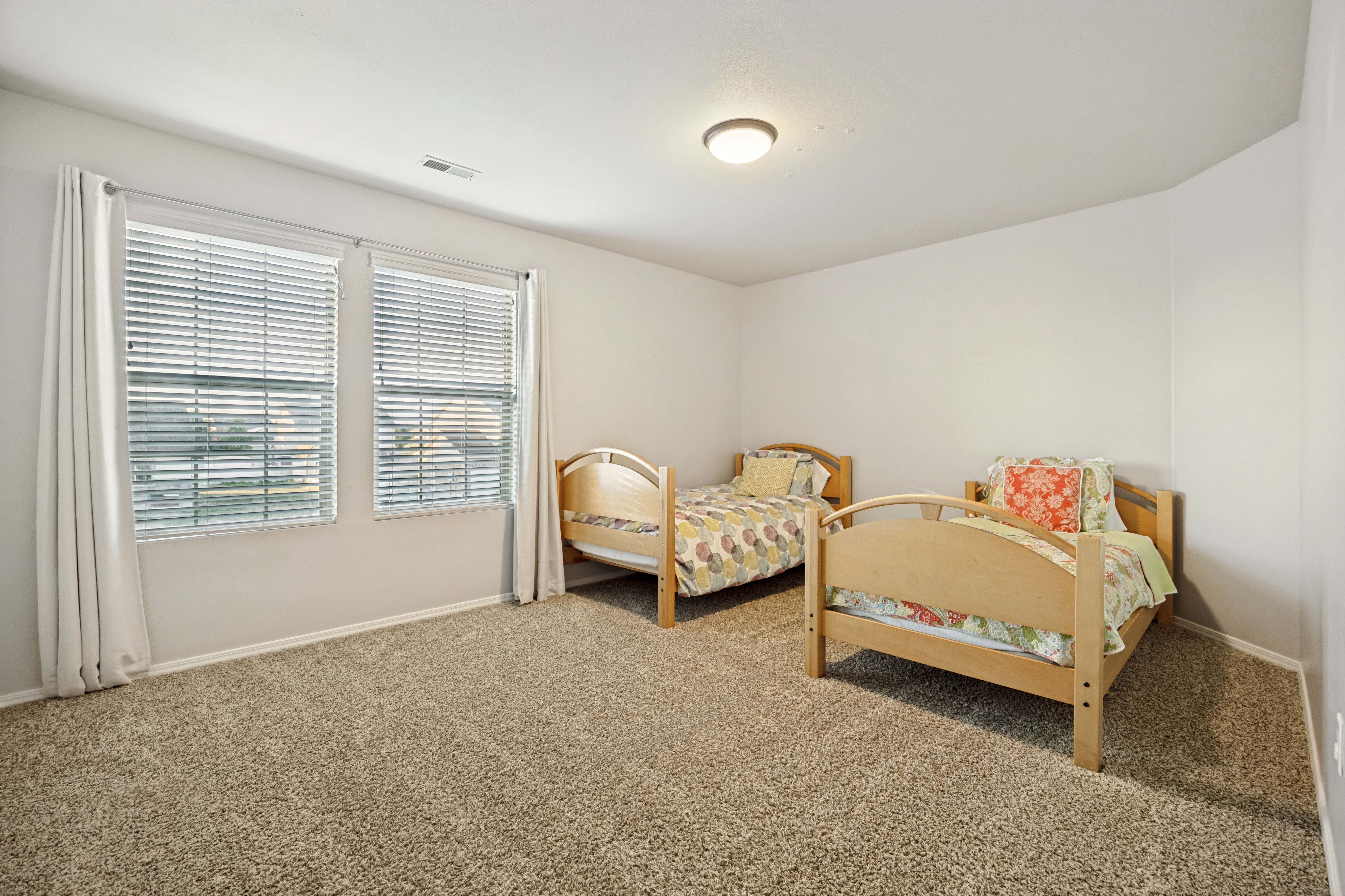 Carpeted room featuring two windows with blinds, a neutral wall color, and a ceiling-mounted light fixture