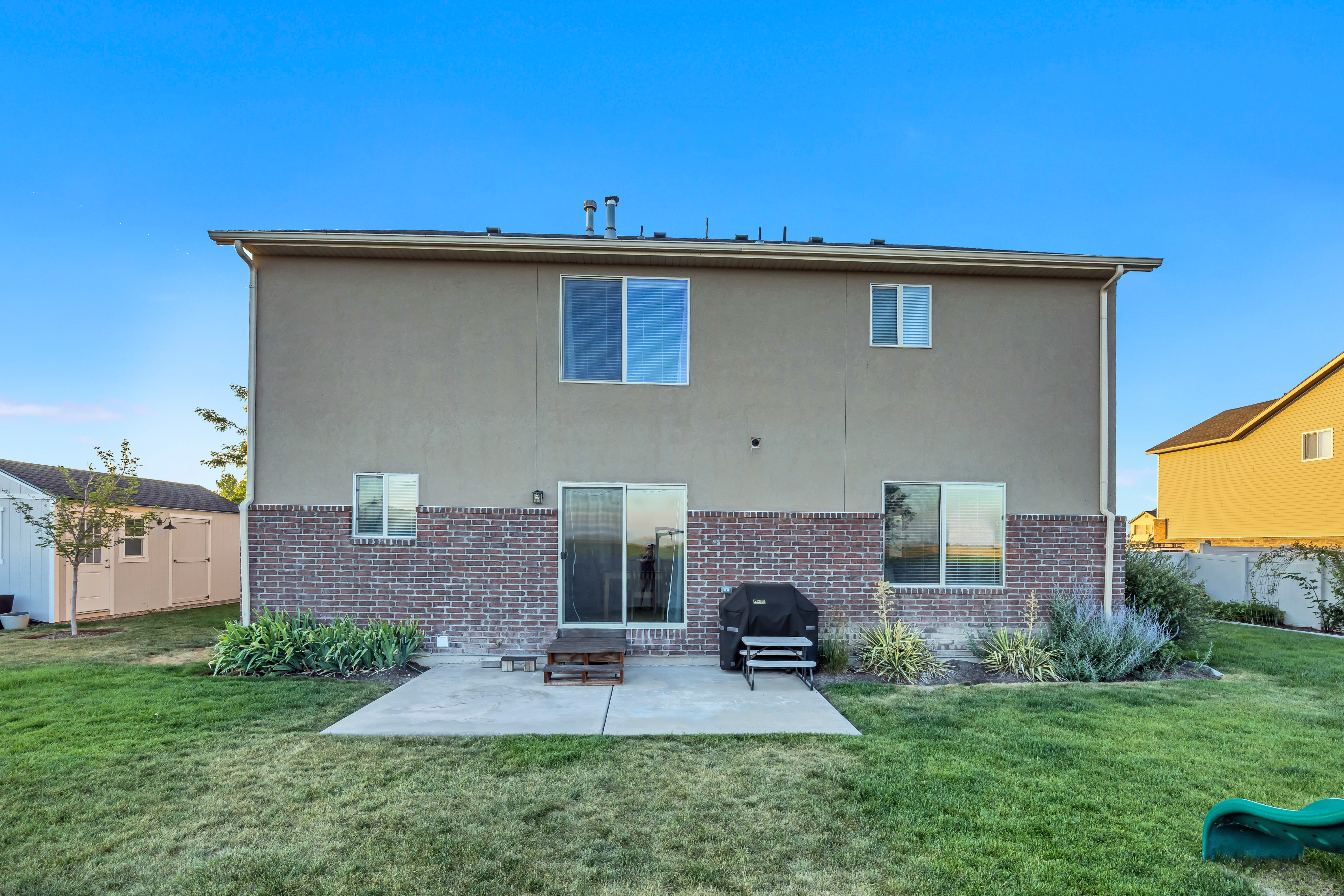 Spacious backyard featuring a concrete patio, sliding glass door access, and a brick and stucco exterior