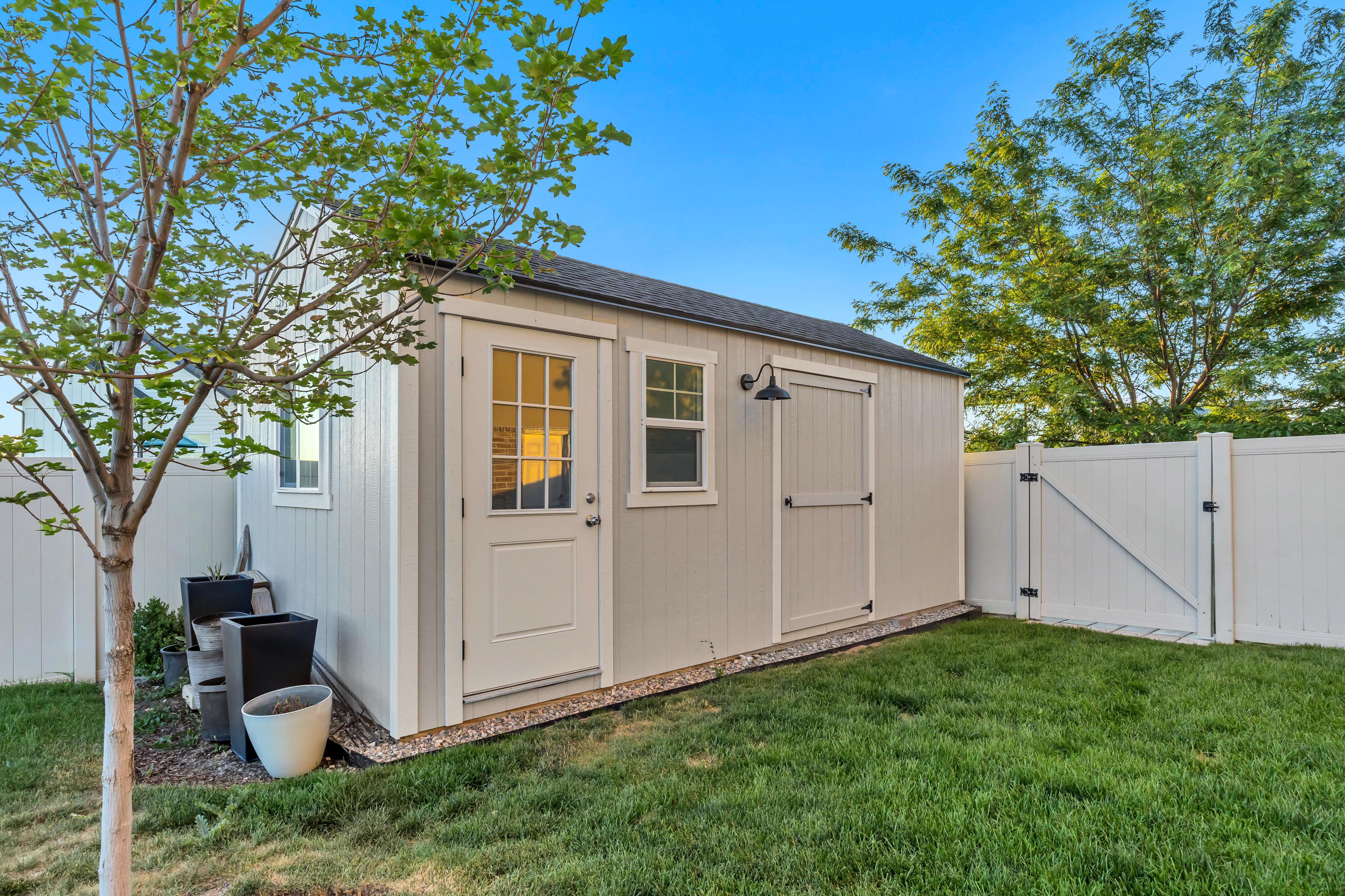Detached storage shed with a panel door, transom window, and a built-in light fixture