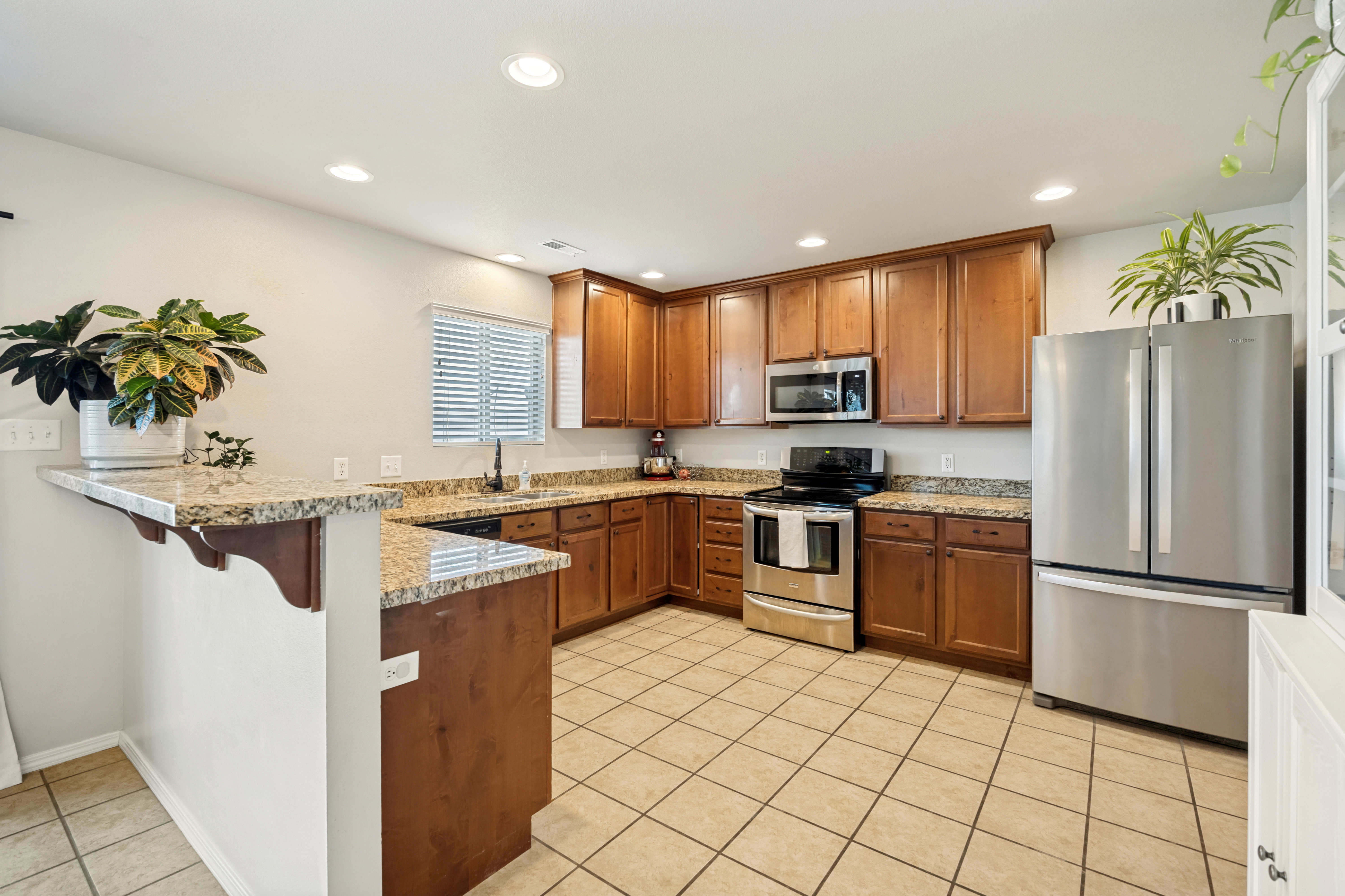 Kitchen featuring a breakfast bar, recessed lighting, wood cabinetry, stone countertops, and stainless steel appliances