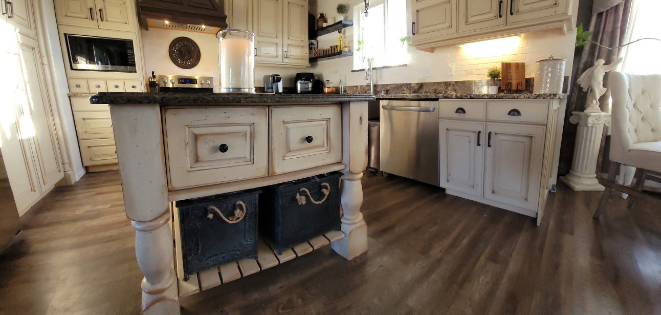 Kitchen island featuring a stone-finish countertop, distressed cream cabinetry, and wood-finish flooring