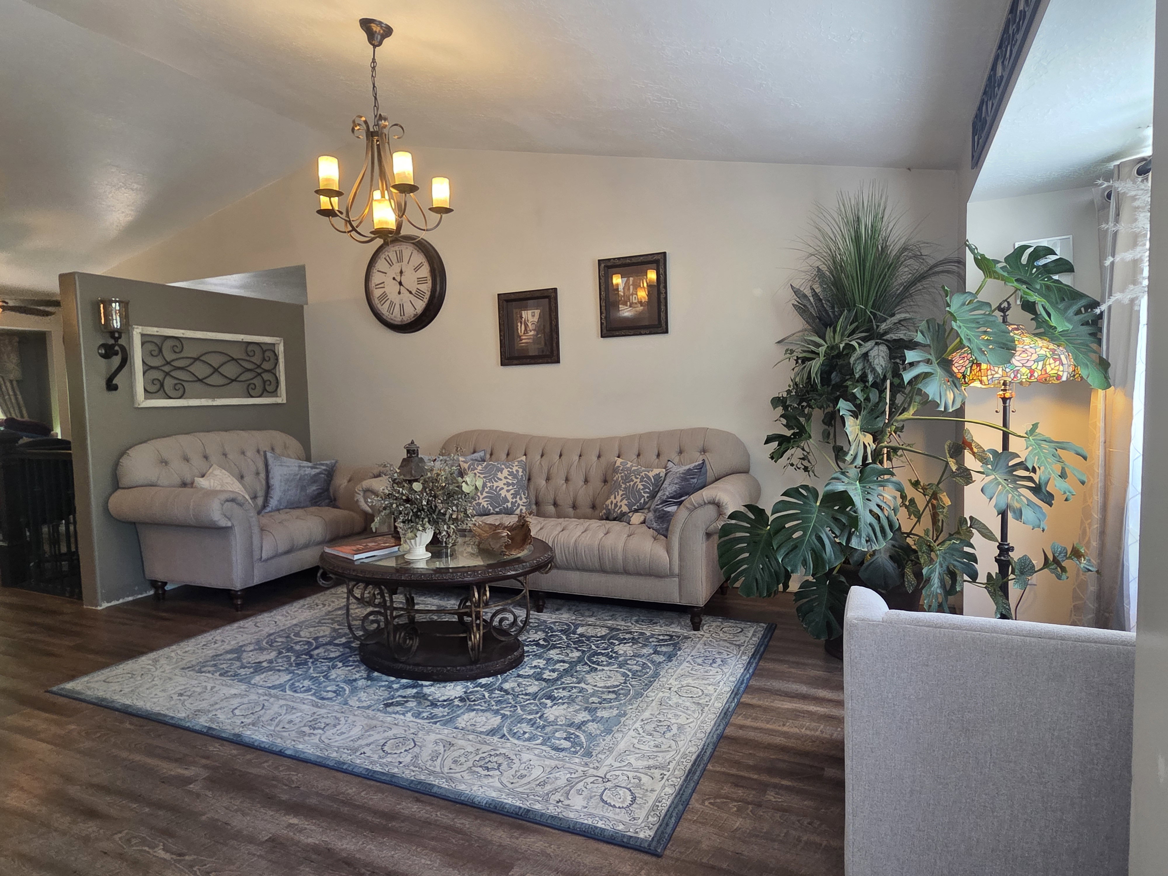 Living area featuring vaulted ceilings, wood-finish flooring, a decorative chandelier, and a partial wall with sconce lighting