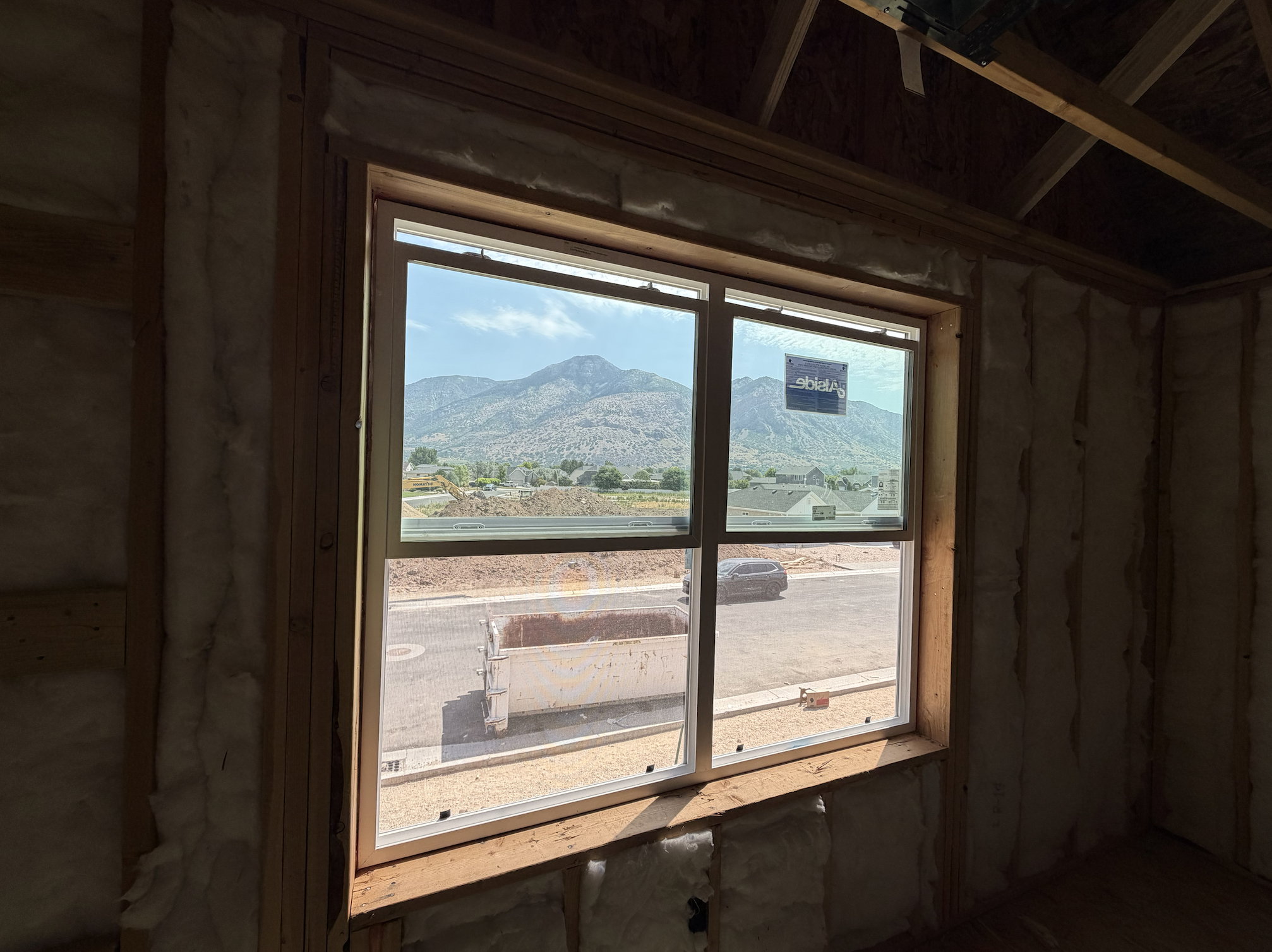 Window framing a mountainous backdrop, showcasing visible structural framing and insulation