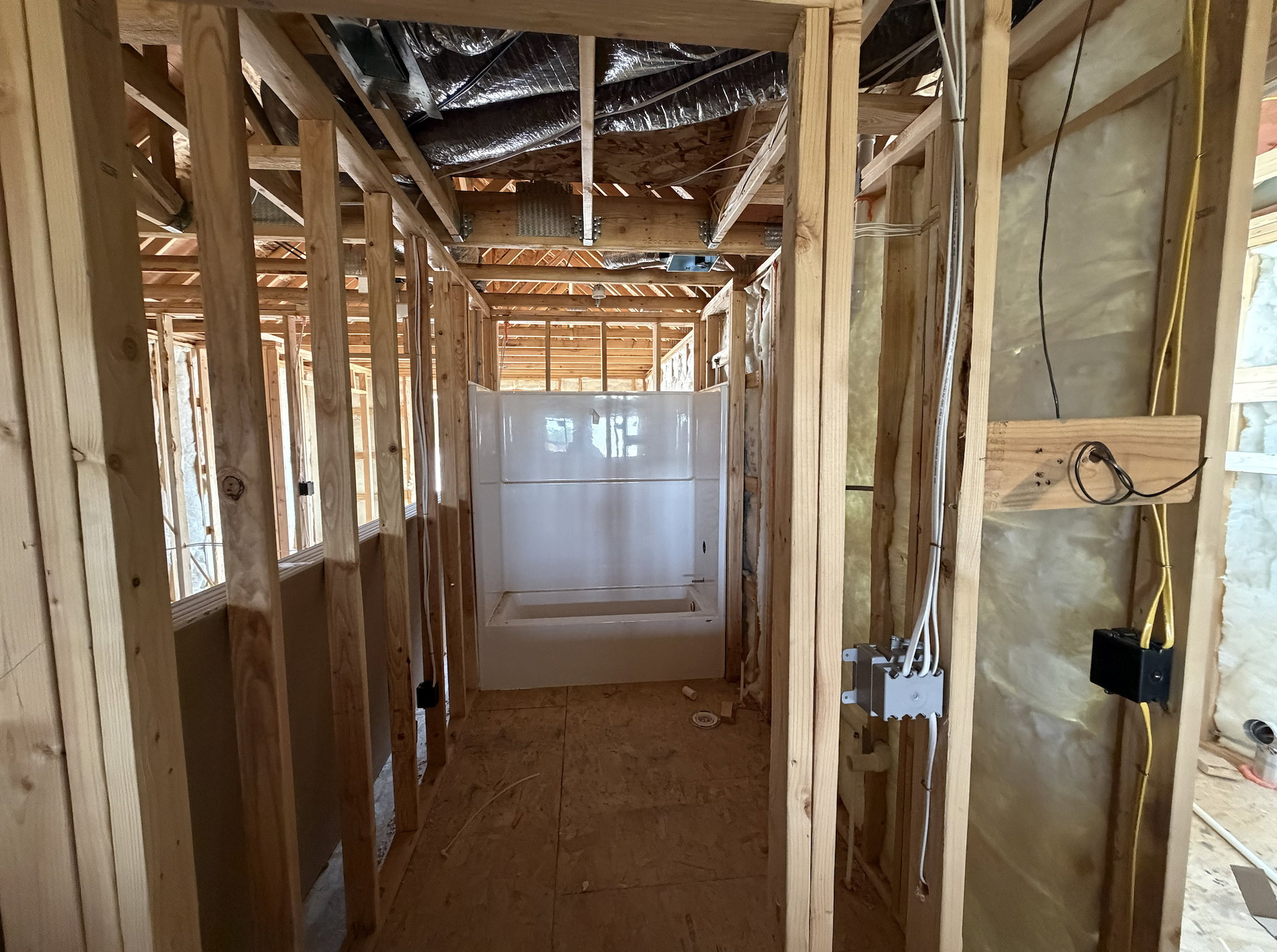 New construction framing with a pre-installed white shower/tub unit