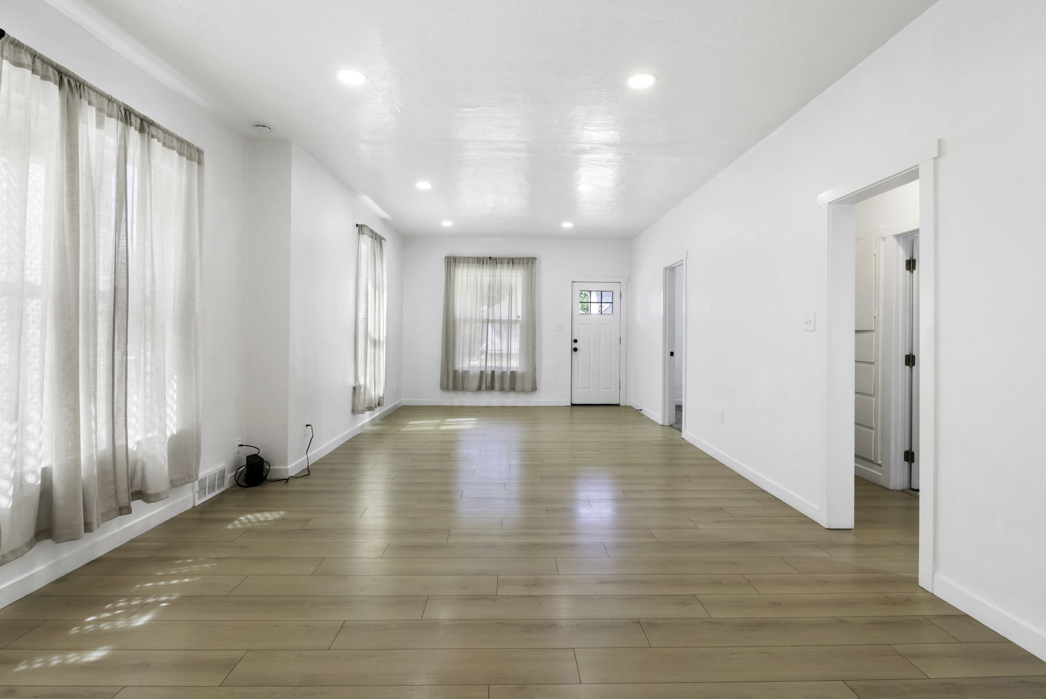 Spacious living area featuring light wood-finish flooring and recessed lighting