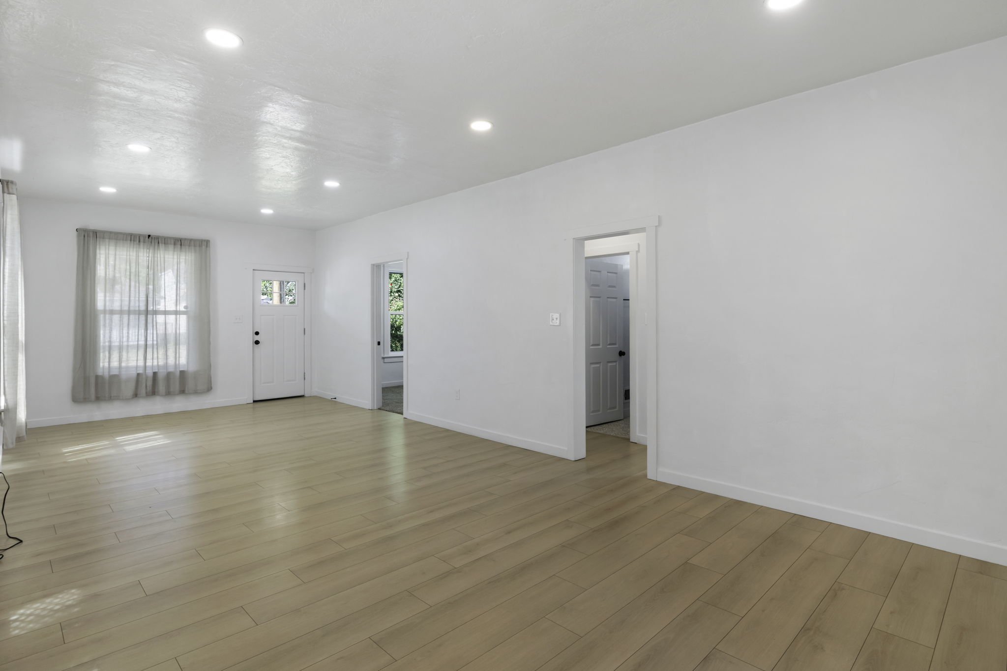 Spacious room featuring wood-finish flooring, recessed lighting, and white baseboards