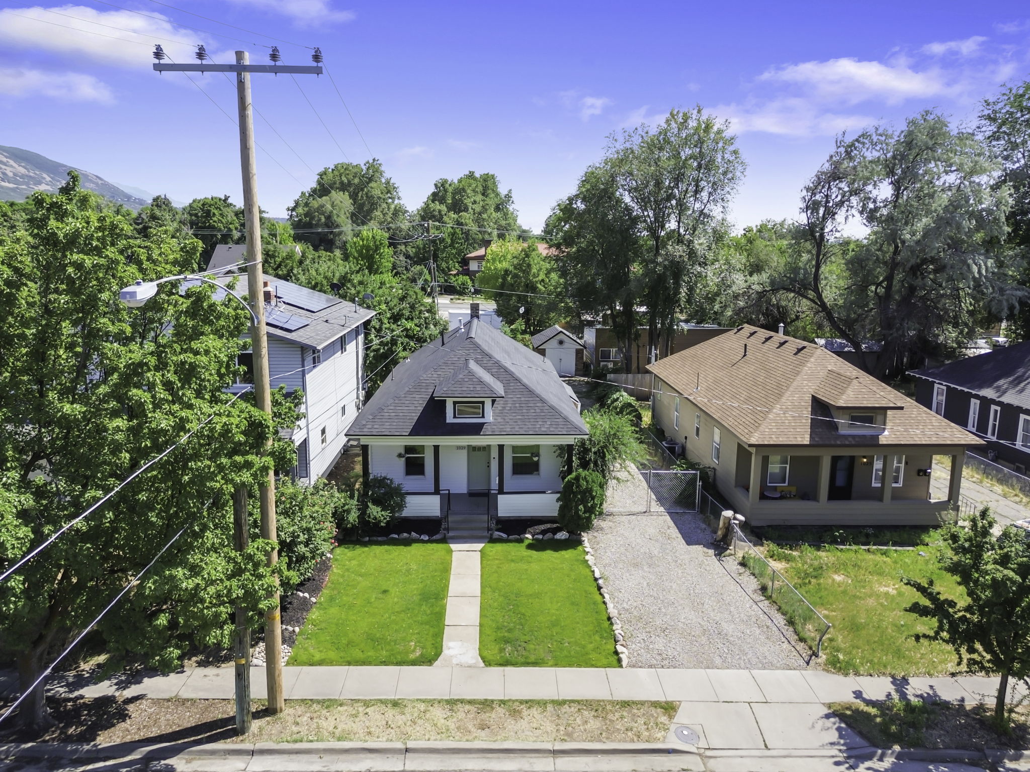 Single-story home featuring a black shingle roof, light-colored siding, and a covered front porch with railings