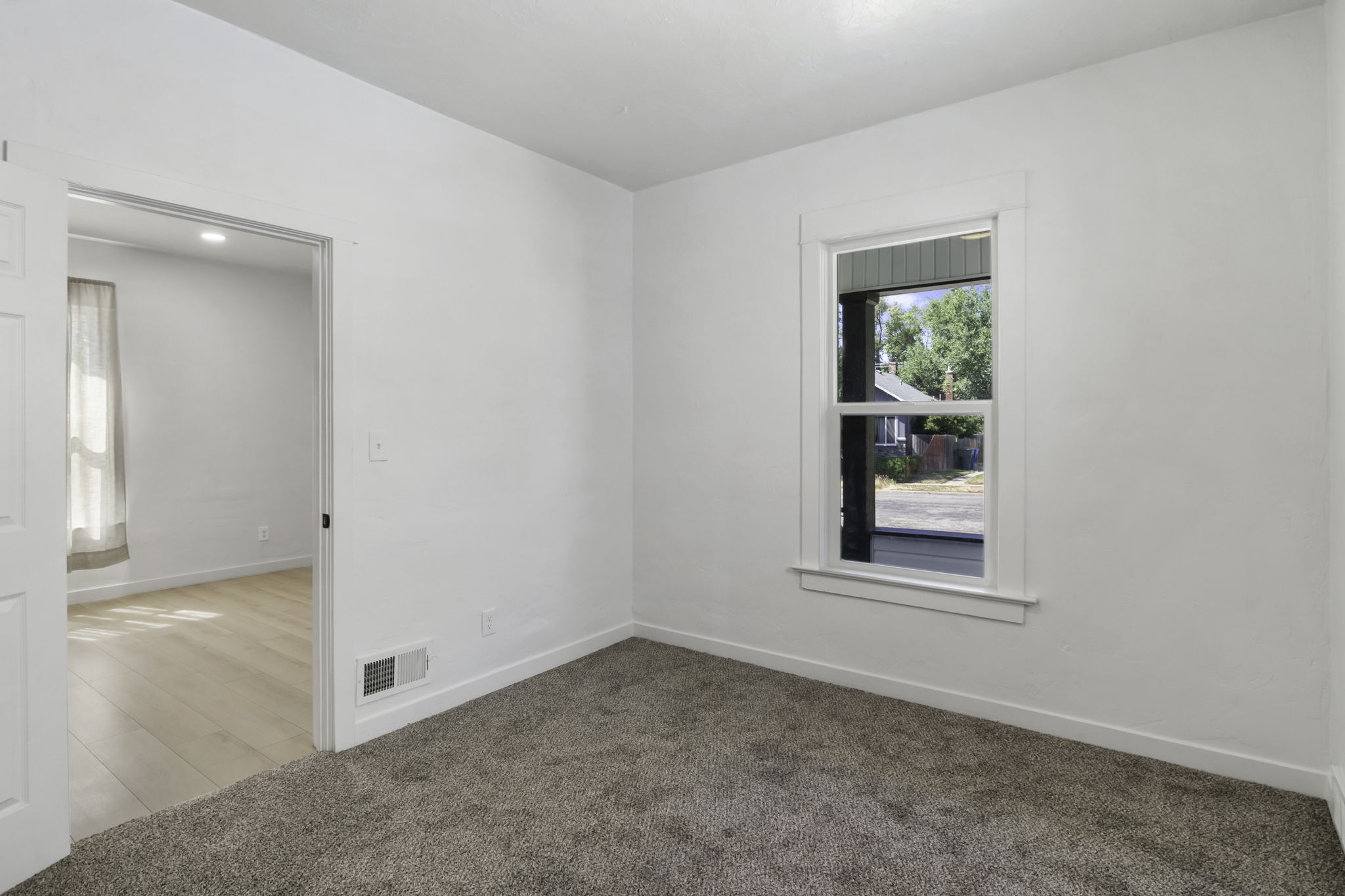 Room featuring neutral-toned carpeting, white walls, and a single window with white trim