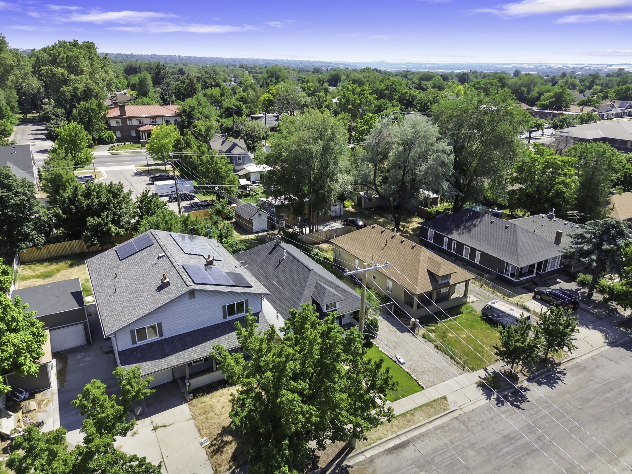 Two-story residence featuring a light blue exterior, dark gray shingle roof, and solar panels
