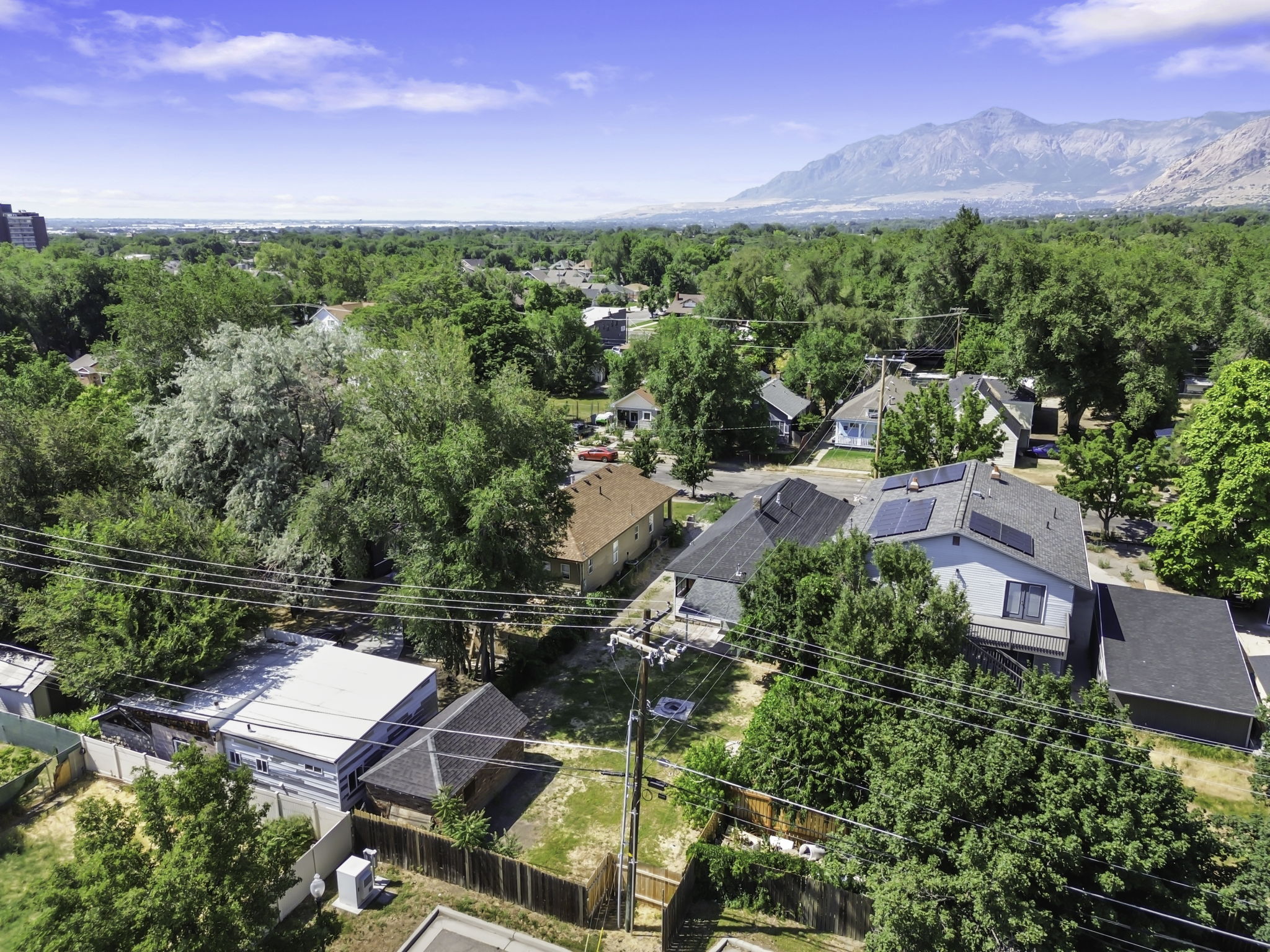Aerial perspective showcasing a residential neighborhood with mature trees and mountain range backdrop