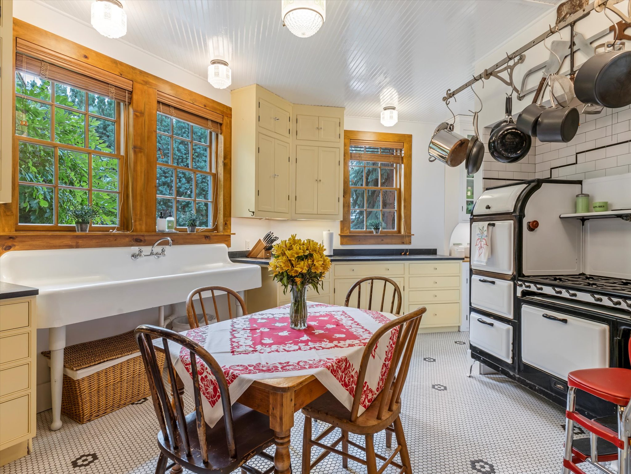 Kitchen featuring a classic white farmhouse sink, mosaic tile flooring, cream-painted cabinetry, a vintage-style range, and natural wood window trim