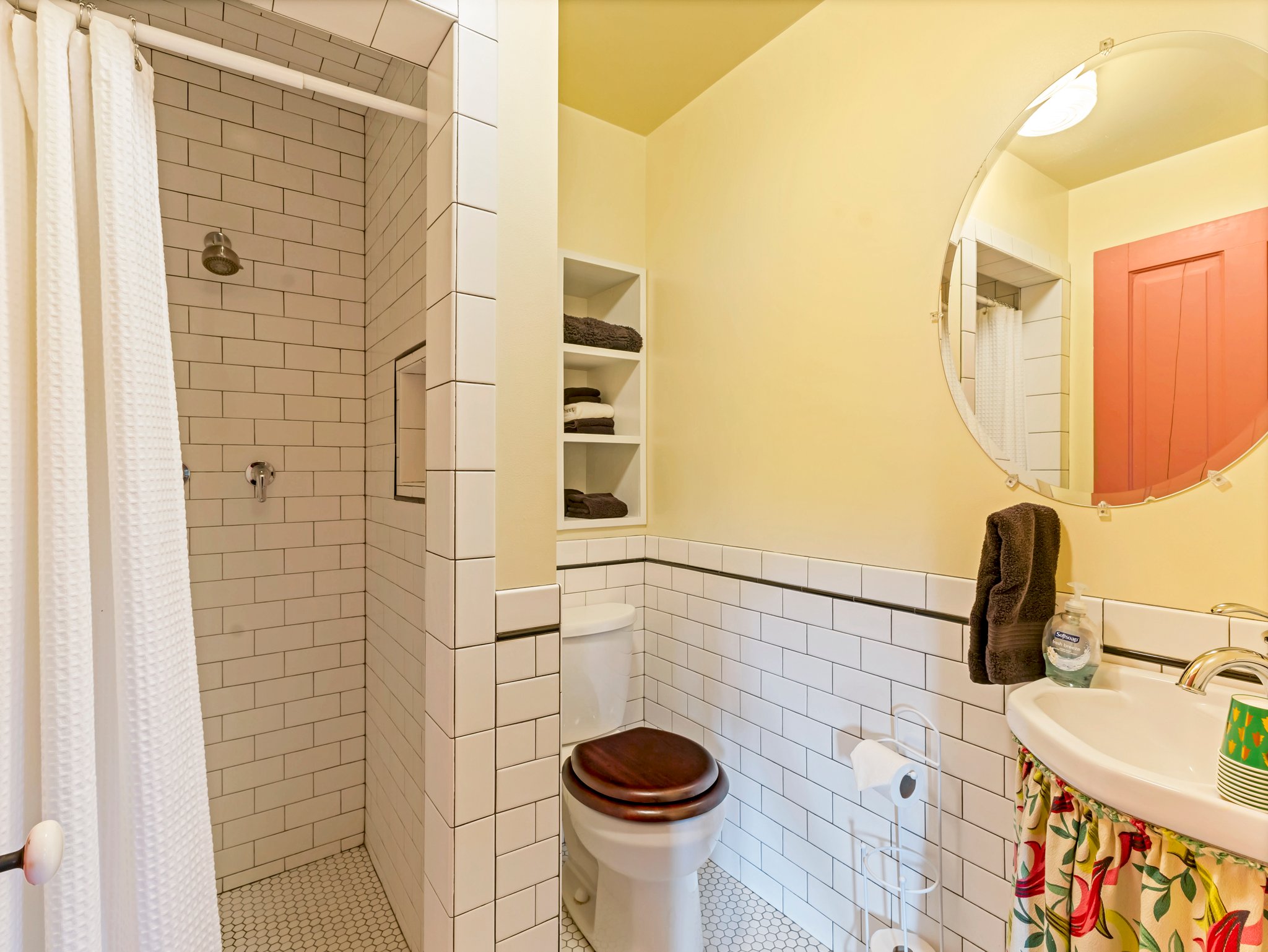 Bathroom featuring subway tile shower, hexagonal floor tile, recessed shower niche, built-in shelving, and a pedestal sink with chrome fixtures