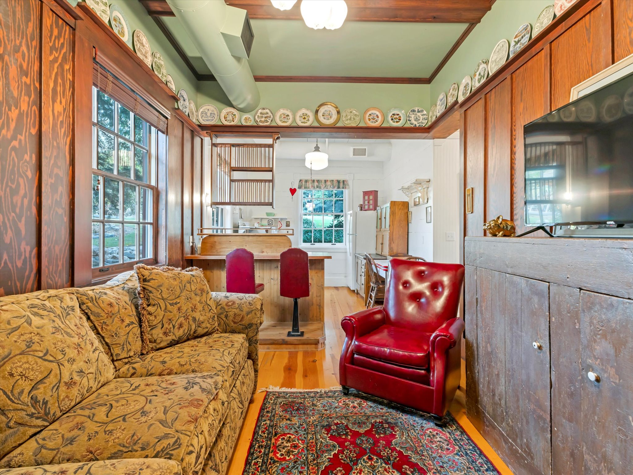 ADU living area featuring exposed wood ceiling beams, hardwood flooring, and a built-in entertainment cabinet