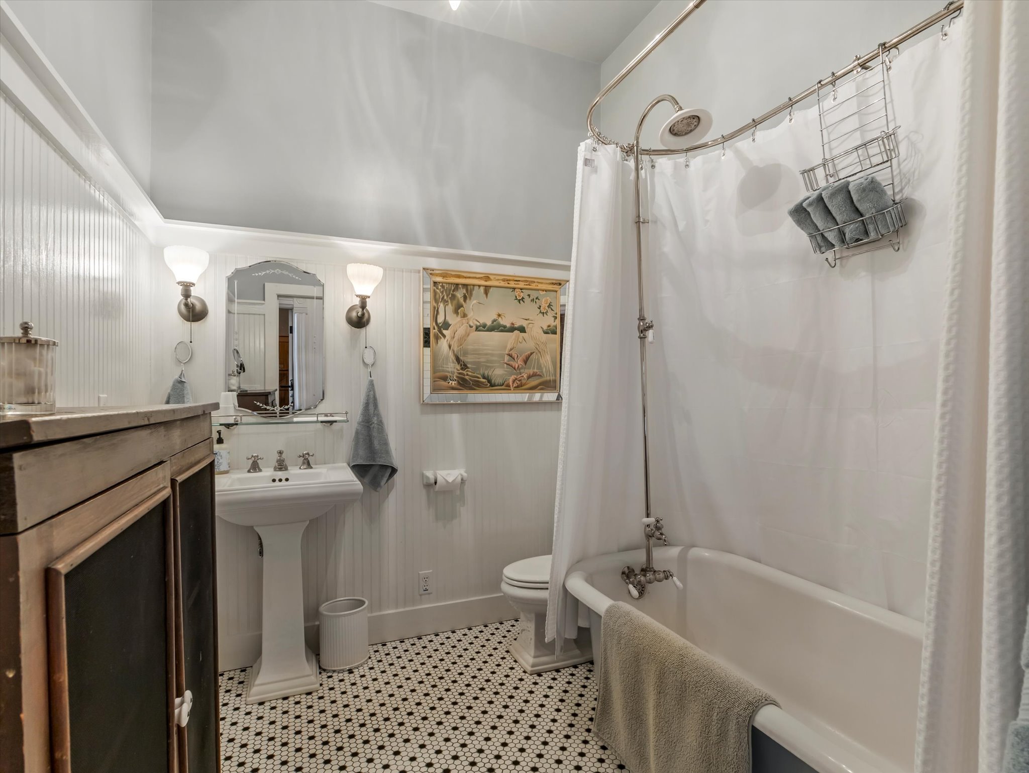 ADU Bathroom featuring a pedestal sink, wall-mounted sconces, and beadboard paneling
