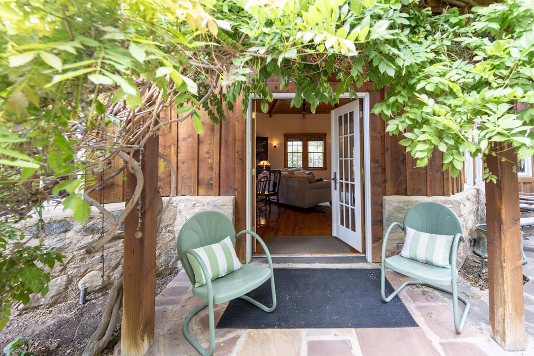Entryway featuring French doors, wood-paneled siding, a stone foundation, and natural stone tile flooring