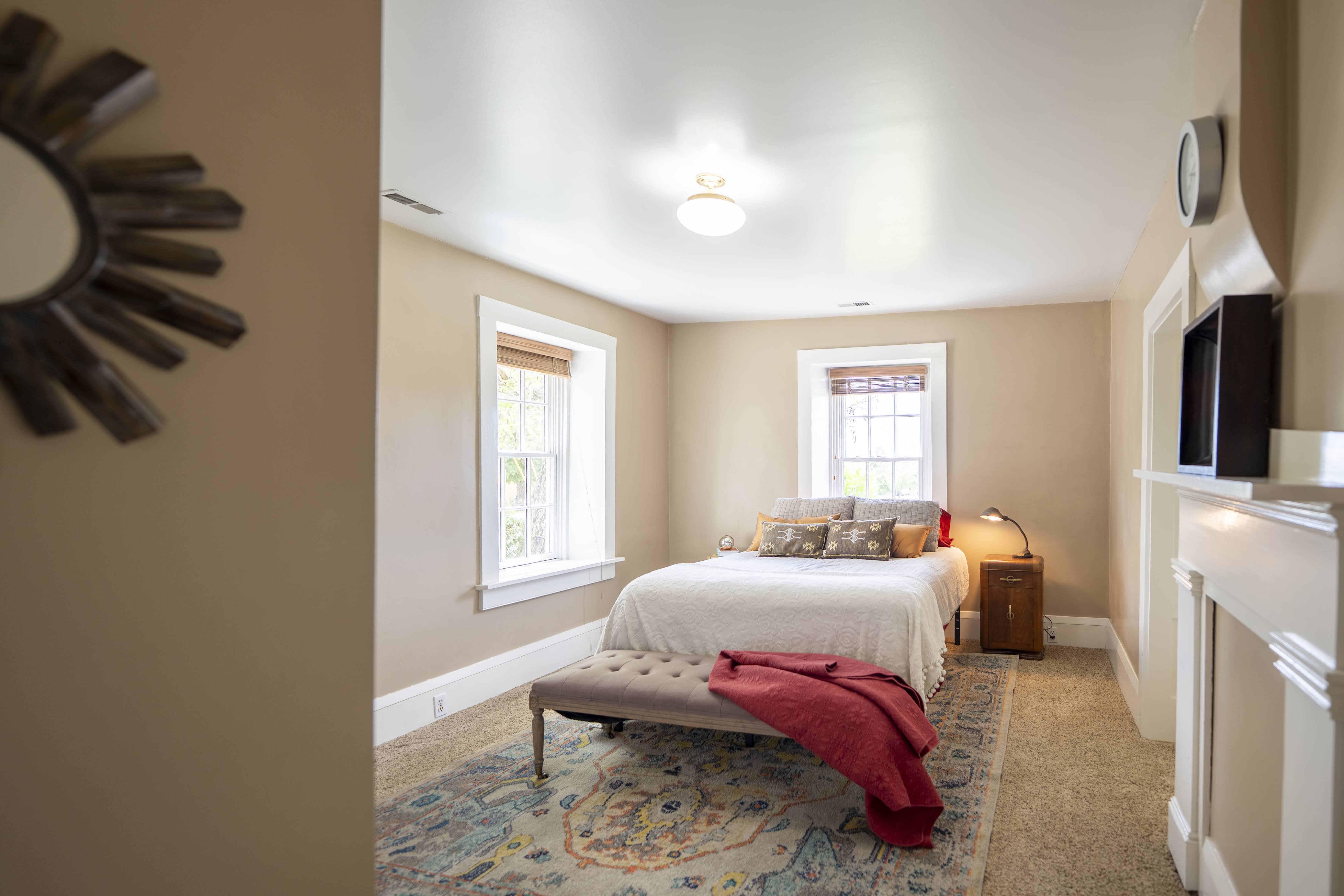 Bedroom featuring two windows with wood blinds, a ceiling-mounted light fixture, and neutral-toned walls