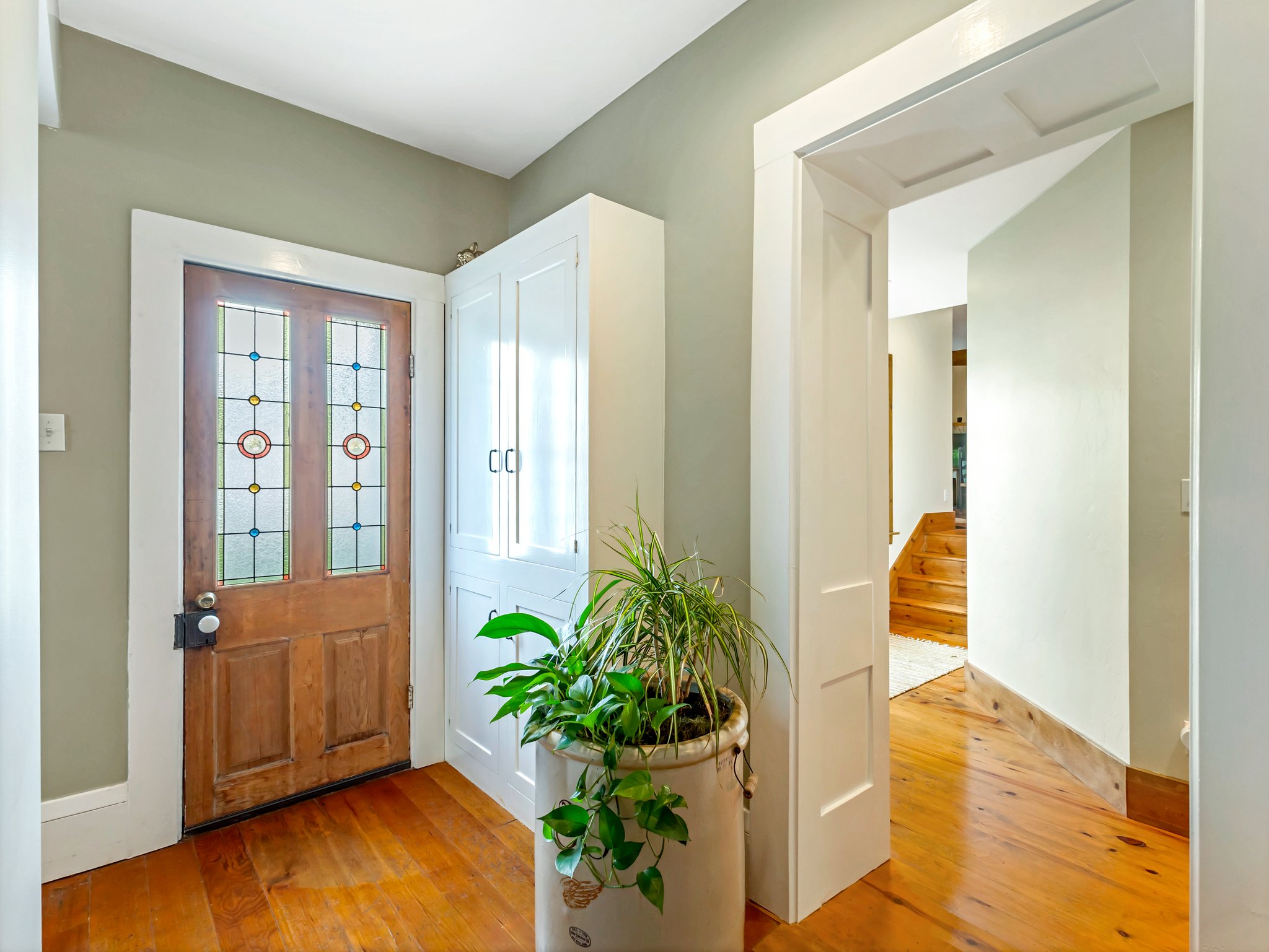 Entryway featuring a wood door with stained-glass panels, rich wood-finish flooring, and white trim