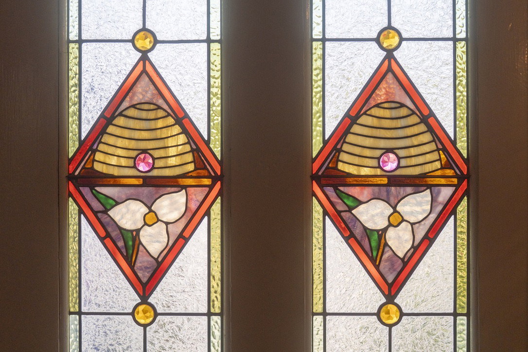 Stained glass window panels featuring beehive and trillium flower motifs