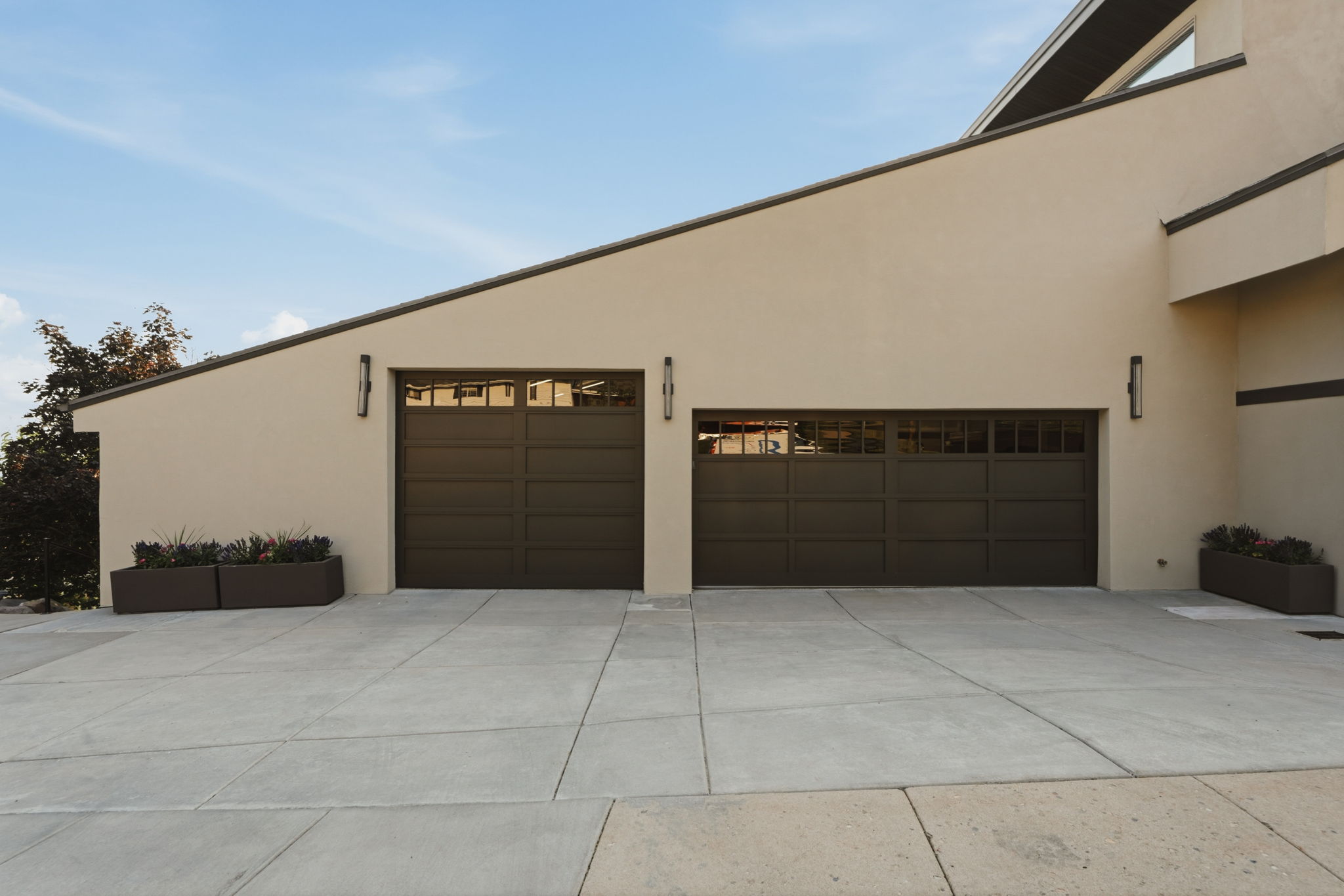 Stucco exterior with two dark paneled garage doors featuring upper window inserts