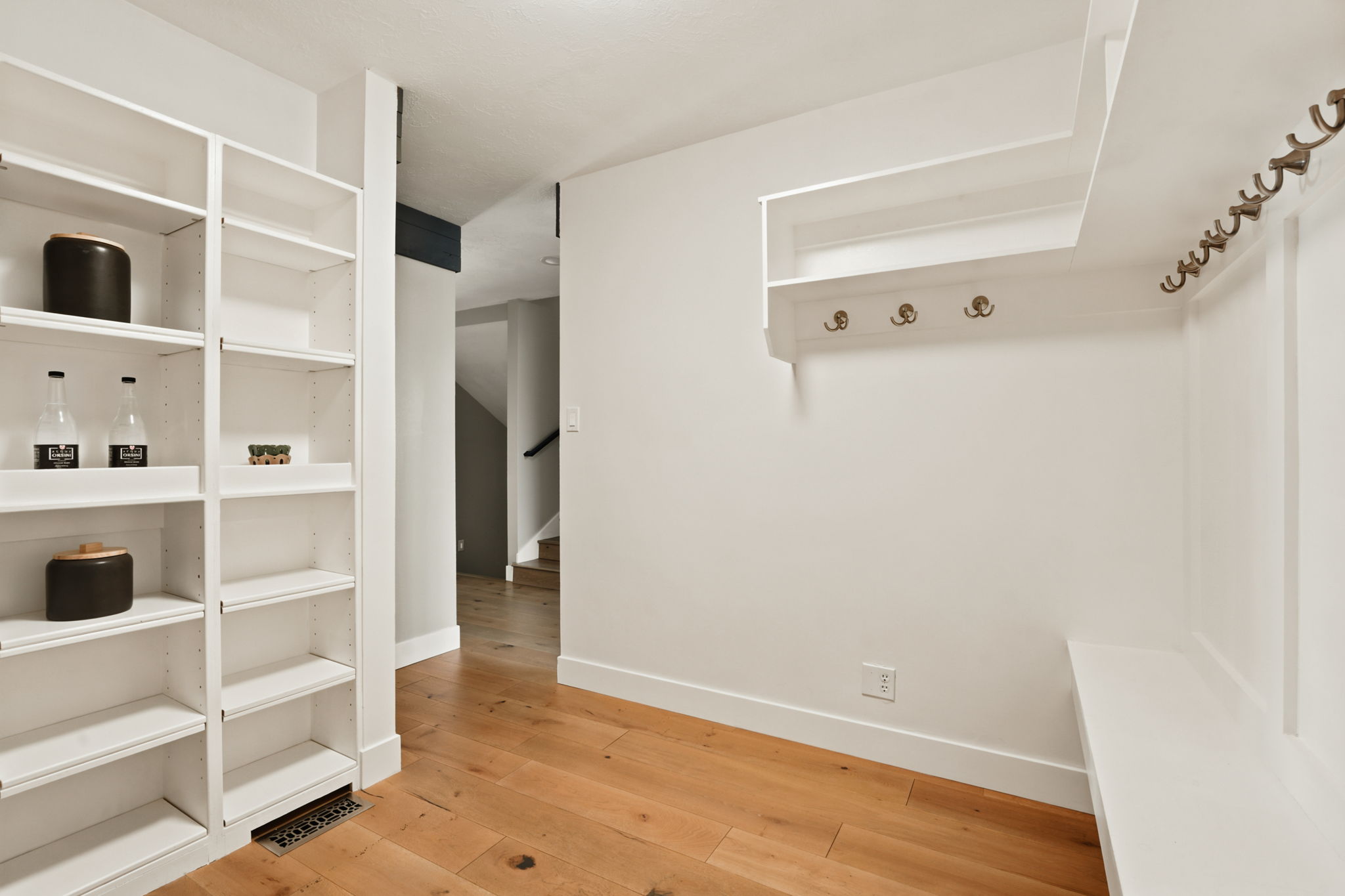Entryway featuring wood-finish flooring, built-in shelving, integrated coat hooks, and a built-in bench
