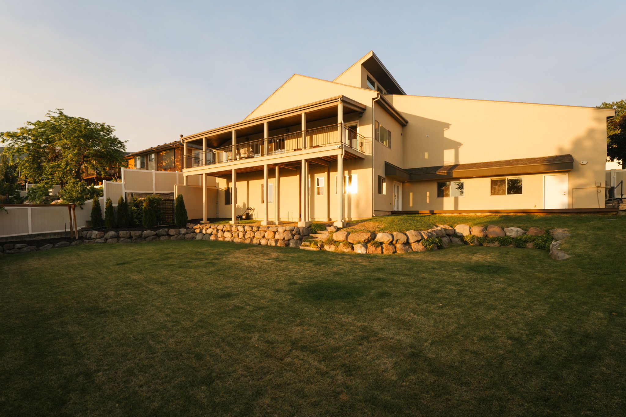 Expansive terraced backyard featuring a manicured lawn, established rock retaining walls, and mature landscaping