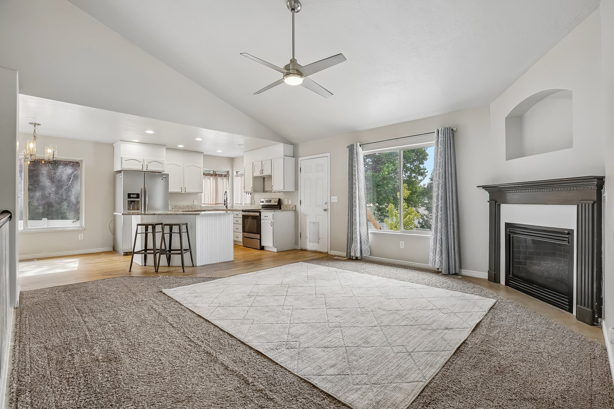 Vaulted ceilings define this open-concept living area, featuring a contemporary ceiling fan with integrated lighting