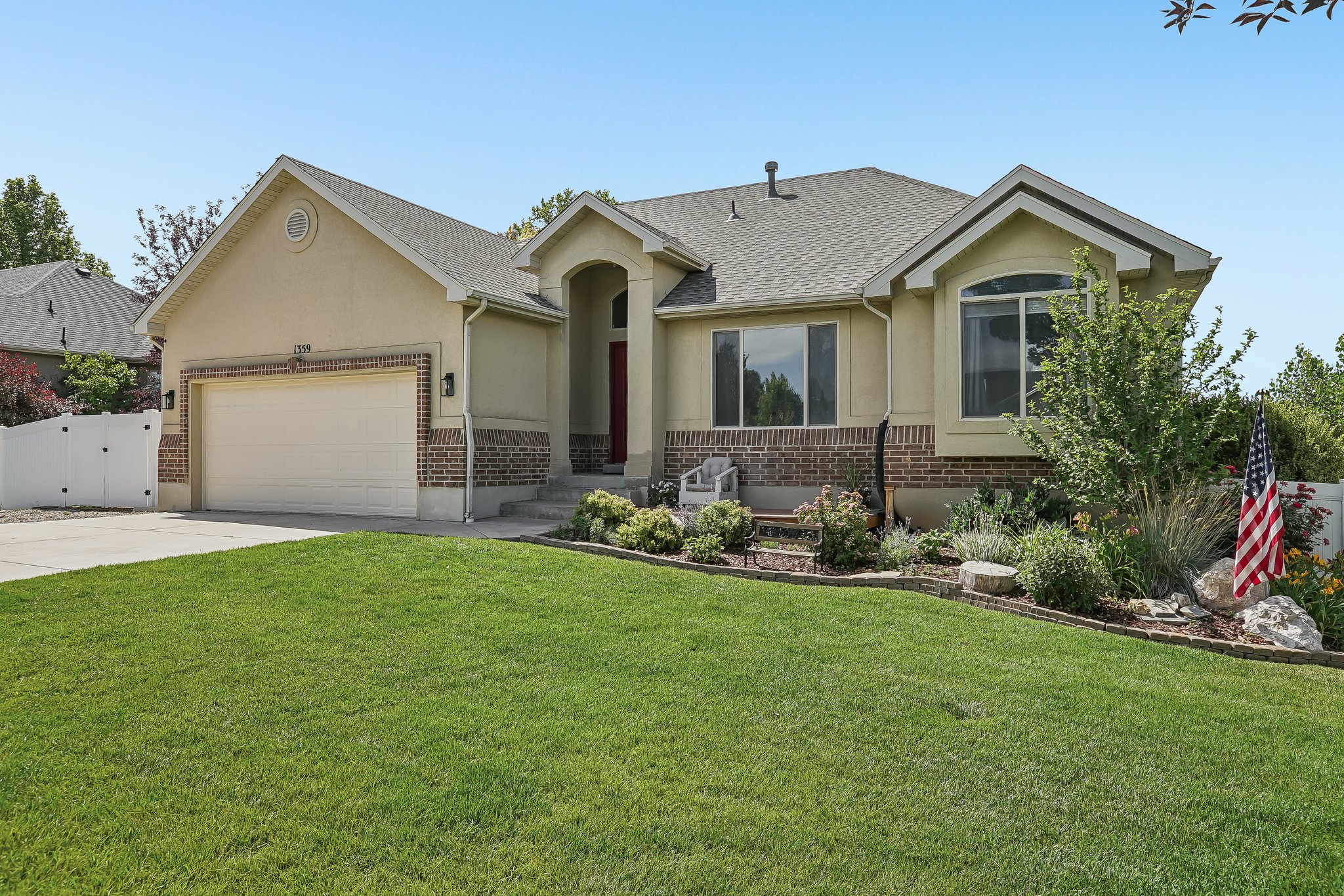 Single-story residence featuring a two-car garage, brick and stucco exterior, arched entry, and a prominent bay window