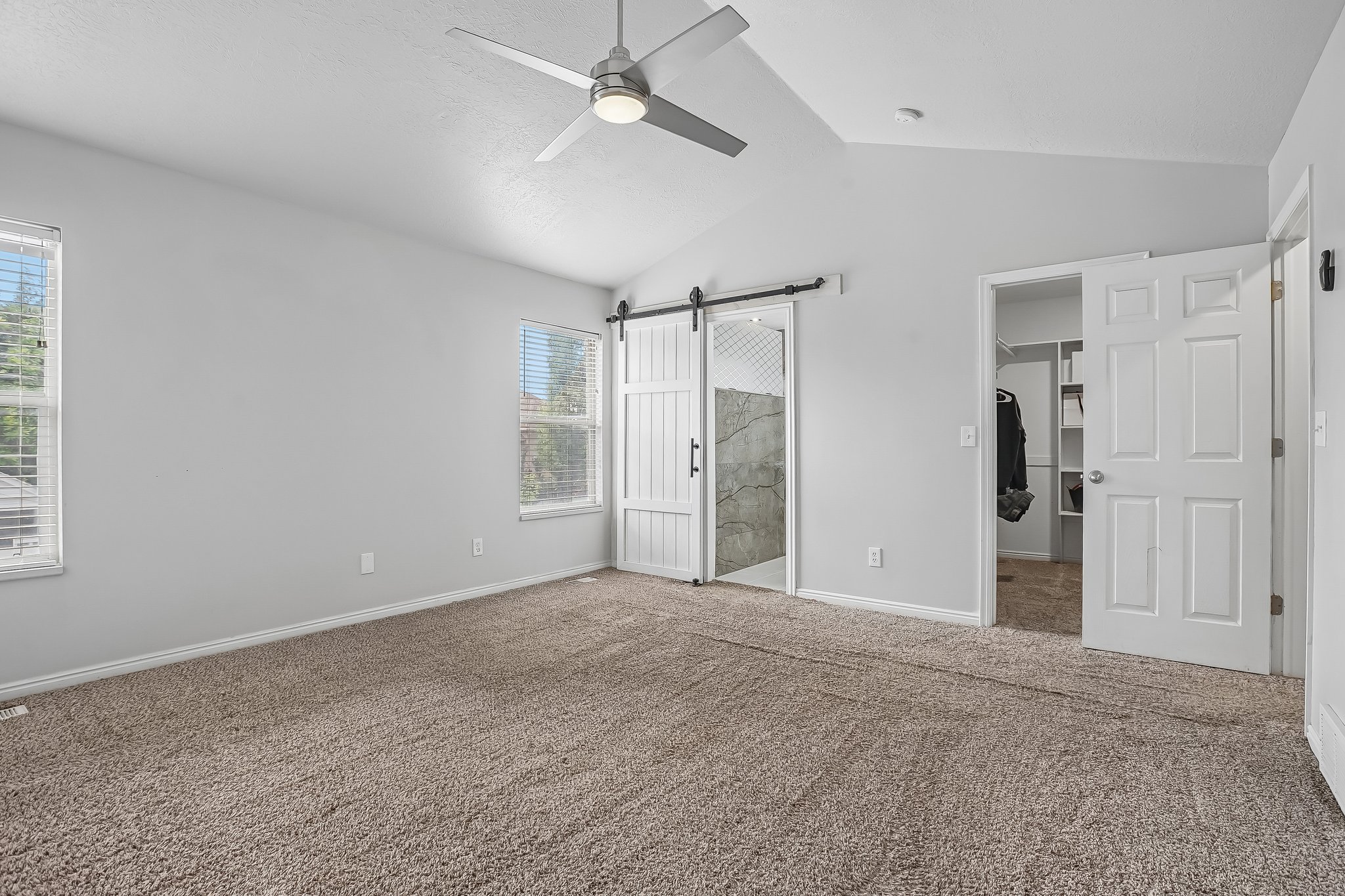 Spacious interior featuring vaulted ceilings and neutral-toned carpeting