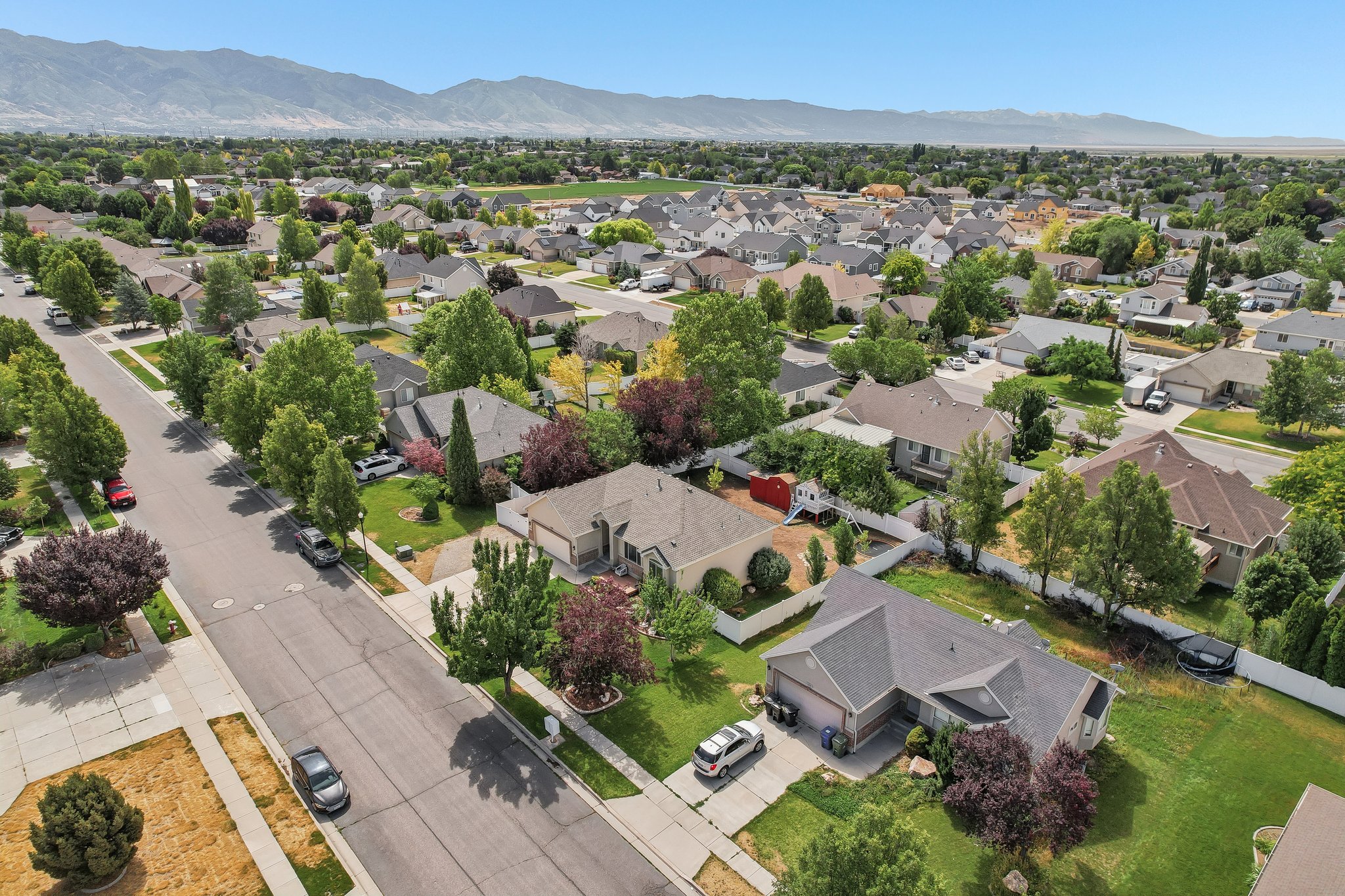 Residential neighborhood featuring mature trees, paved streets, and mountain ranges in the distance