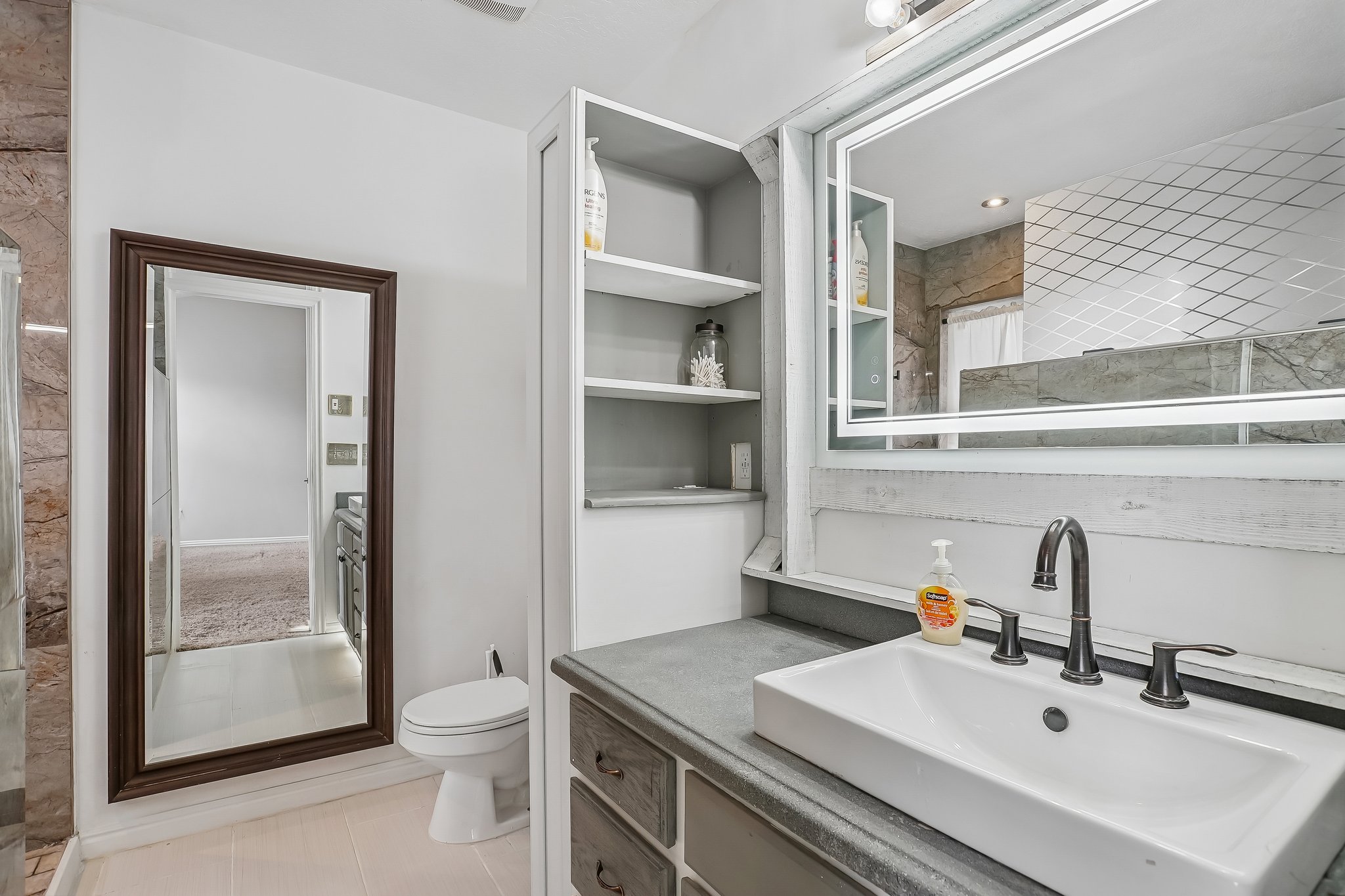 Bathroom vanity featuring a rectangular vessel sink, dark bronze faucet, and a large illuminated mirror