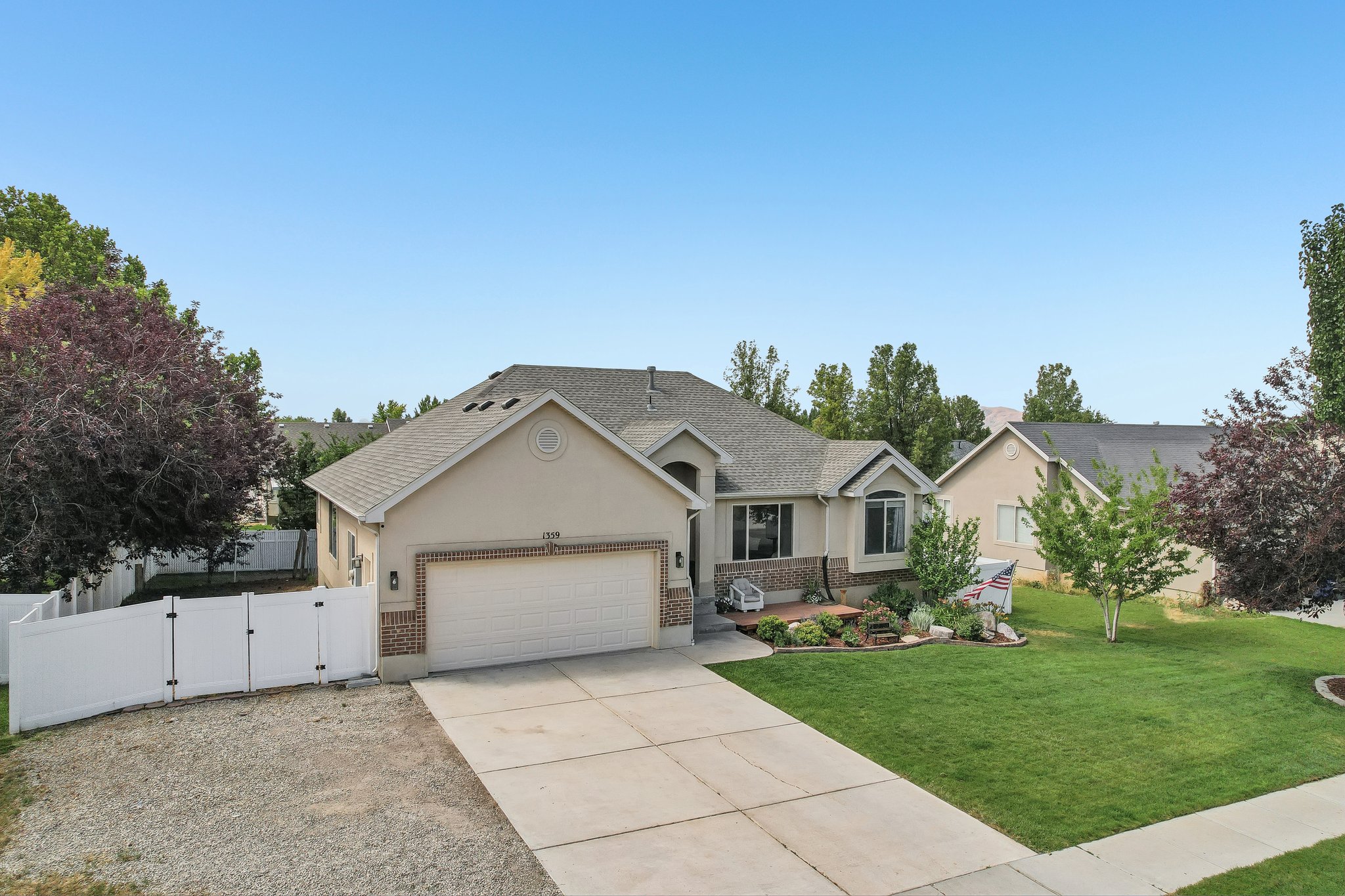 Ranch-style residence featuring a two-car garage, manicured front lawn, and mature landscaping