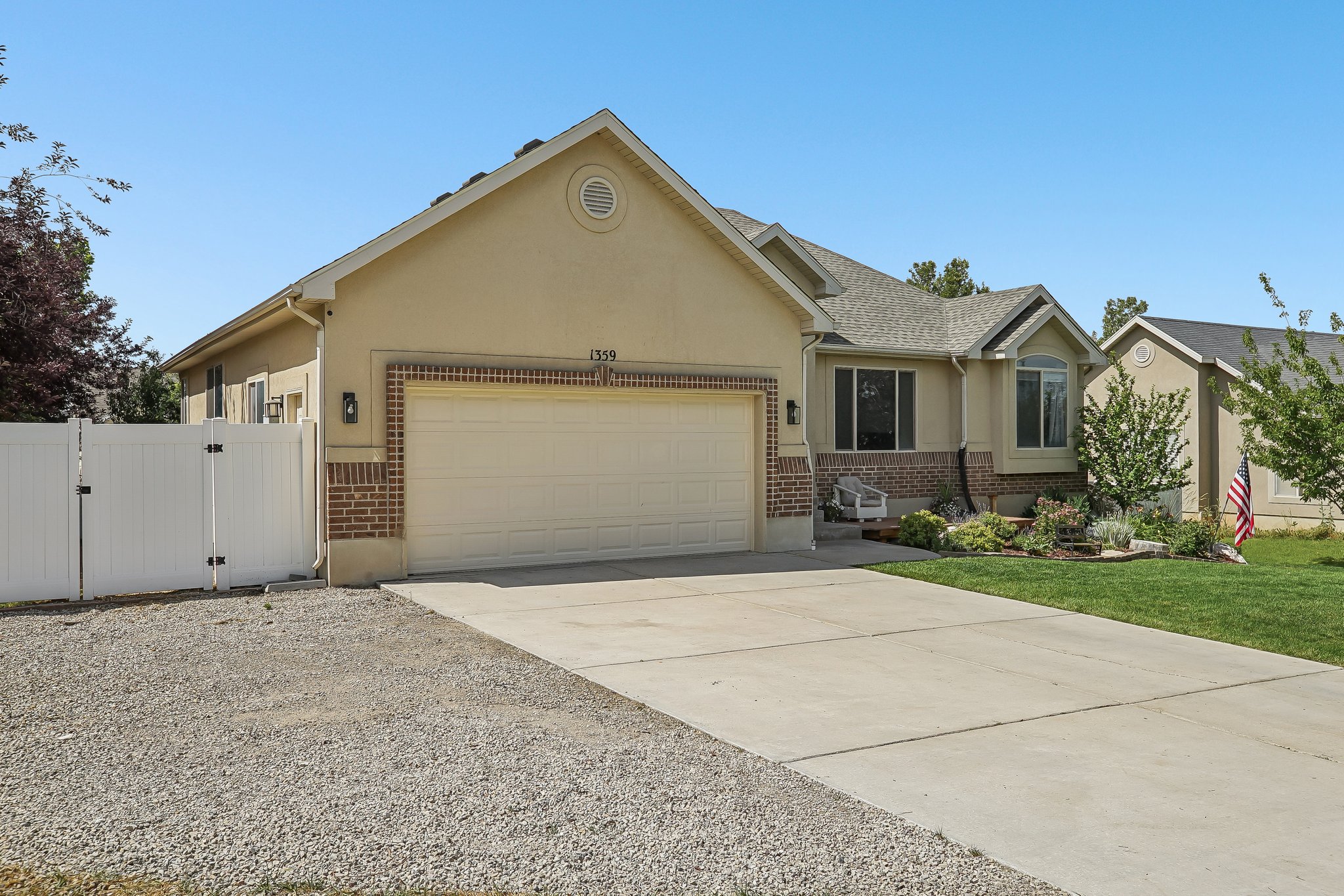Stucco and brick exterior with a two-car garage, concrete driveway, and front lawn