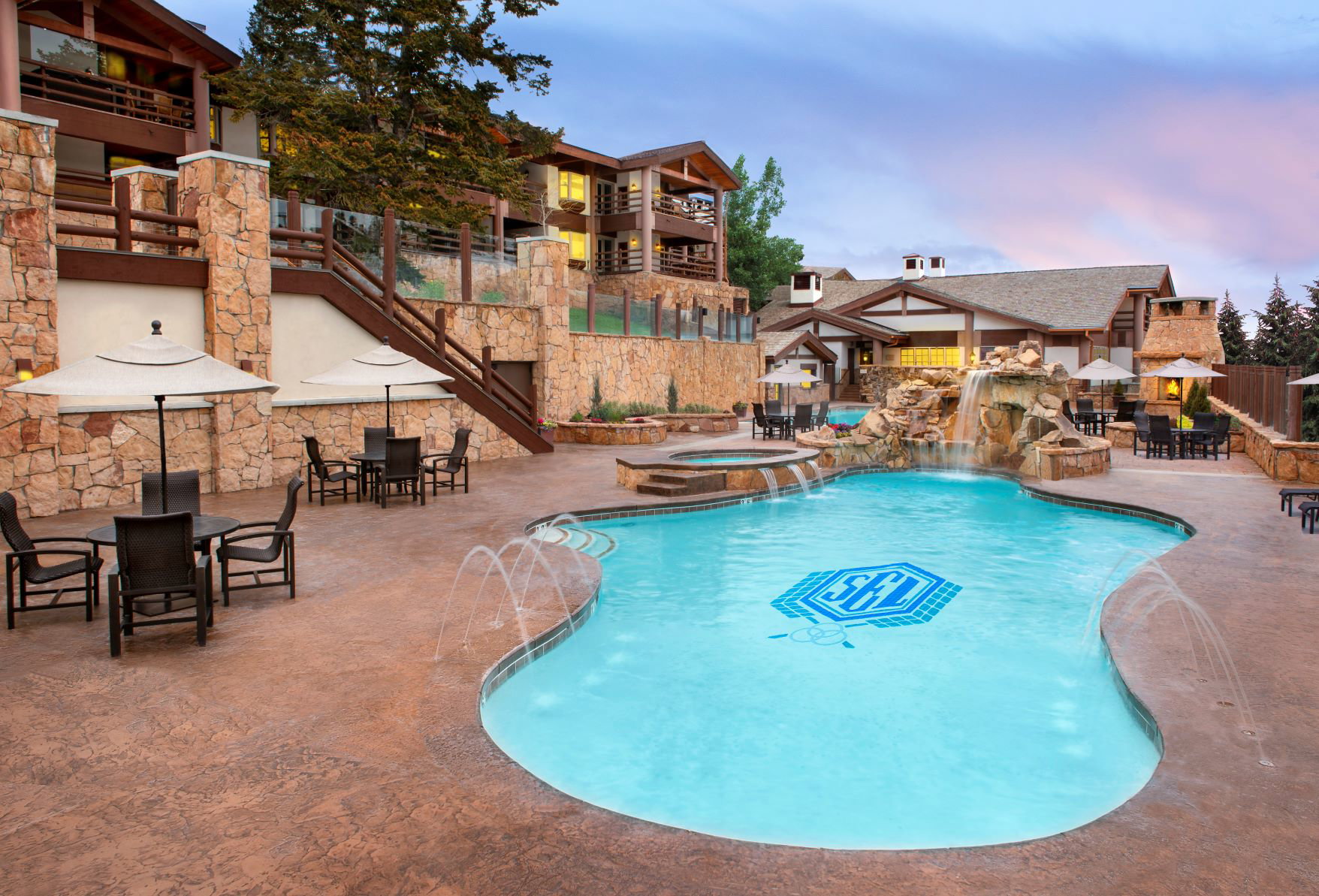 Resort-style pool area featuring a freeform pool with integrated spa and rock waterfall