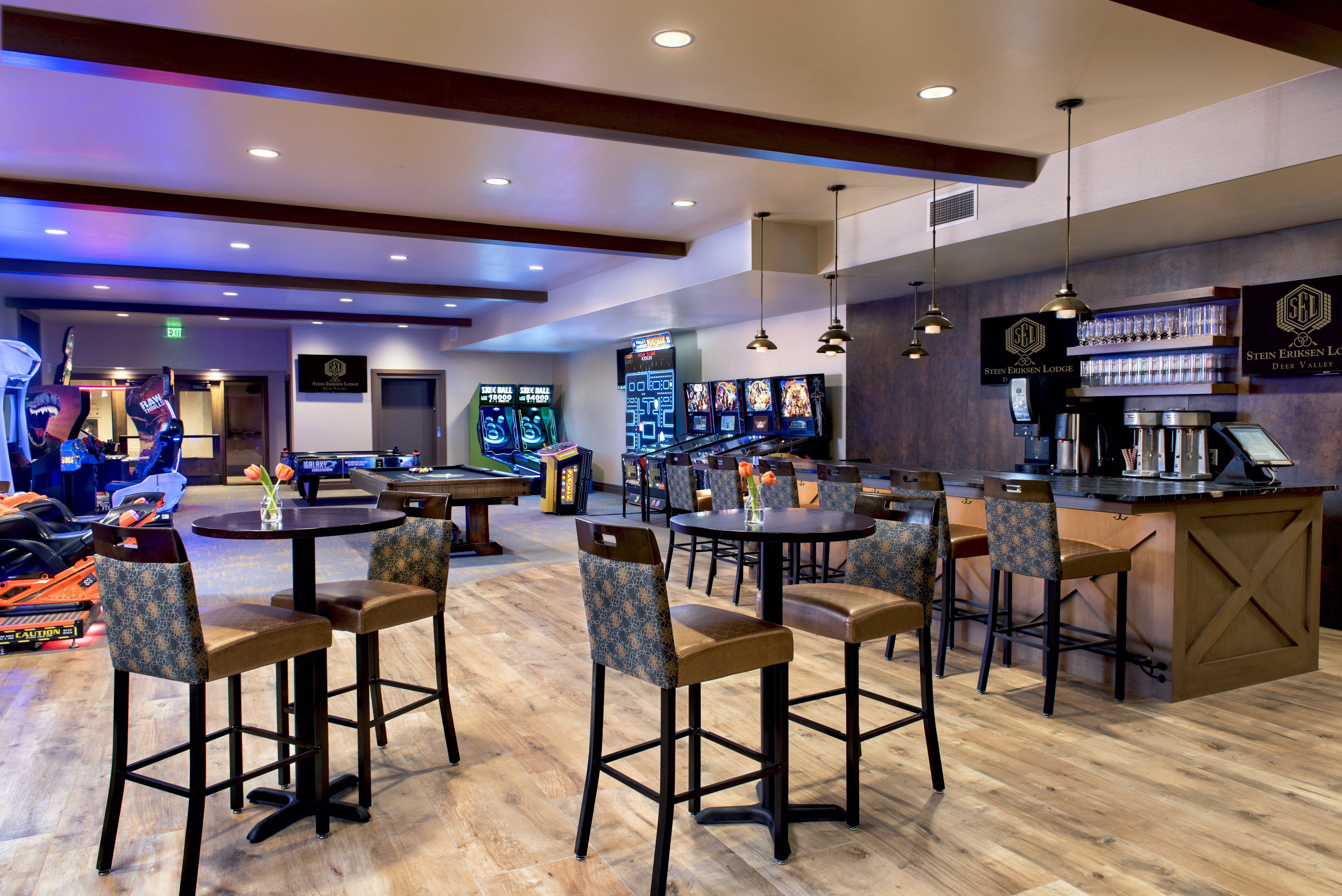 Lounge area featuring wood-finish flooring, a built-in bar with dark countertops, recessed lighting, and exposed ceiling beams