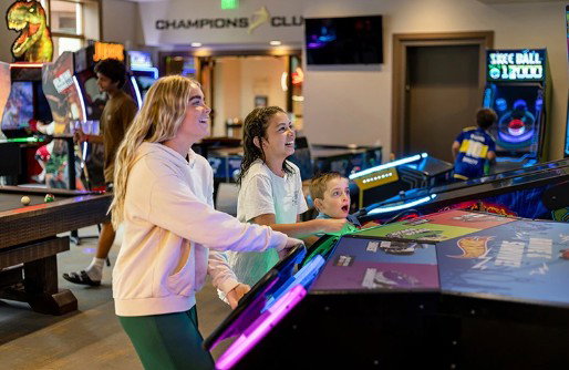 Entertainment area featuring multiple arcade games, a billiards table, and overhead "Champions Club" signage