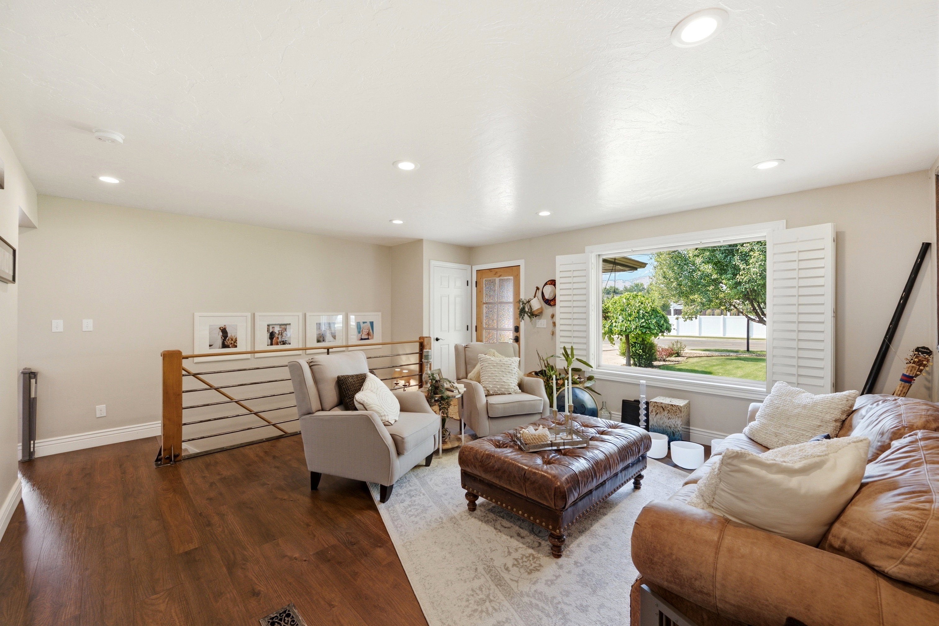 Open concept living area featuring wood-finish flooring, recessed lighting, and a white plantation-shuttered window