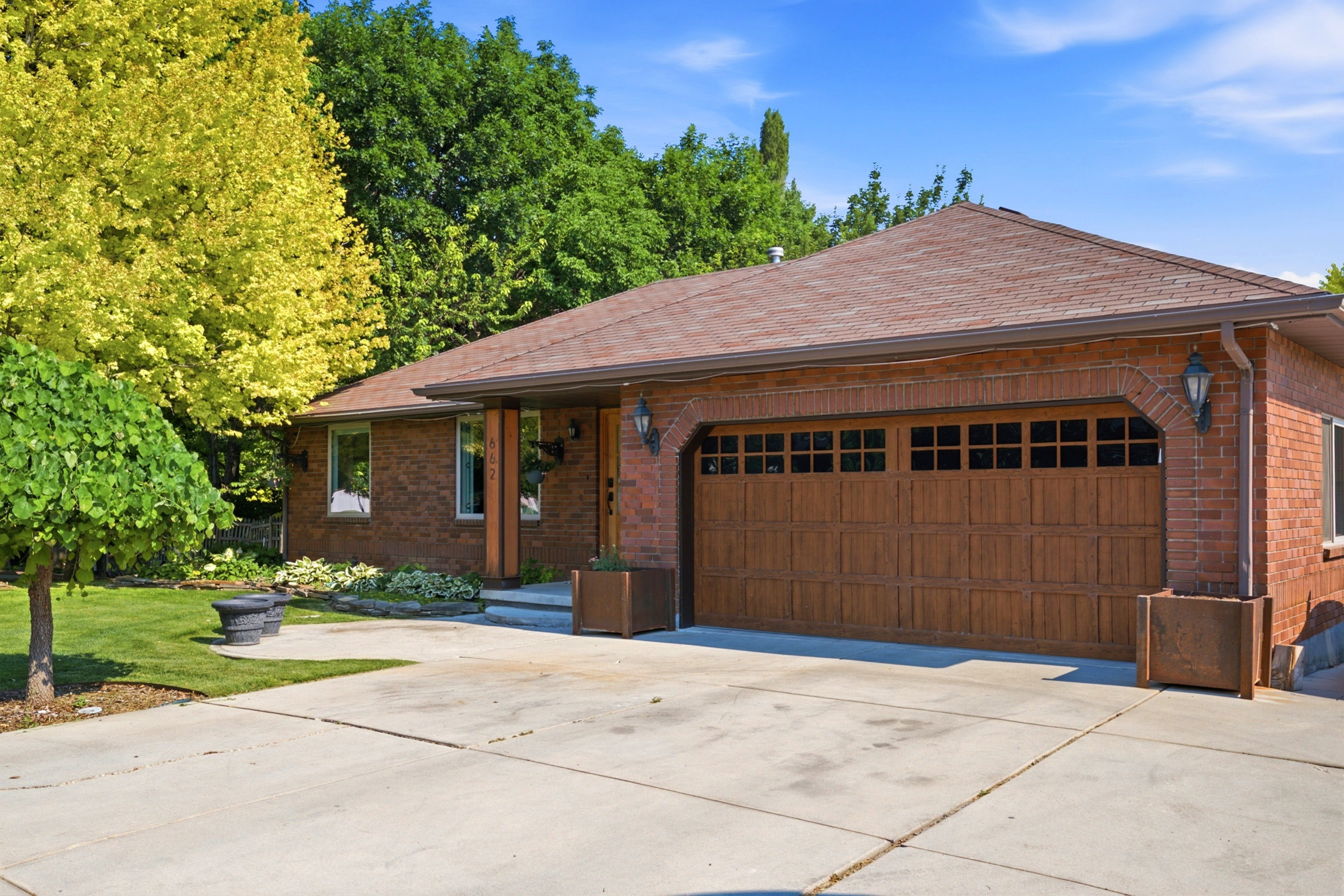 Brick exterior featuring a wood-finish garage door with window inserts and an arched brick detail
