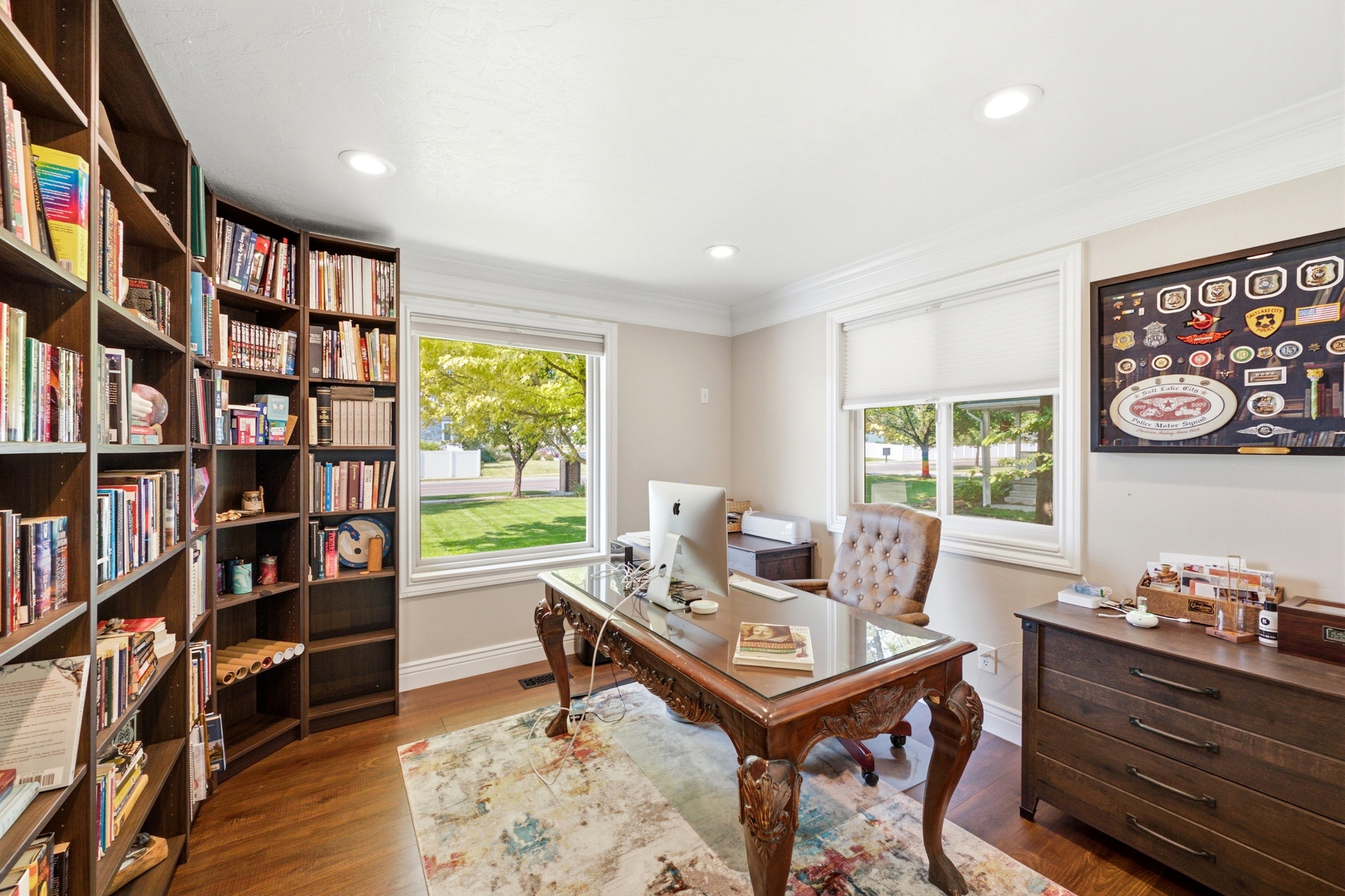 Dedicated office space featuring extensive built-in shelving, rich wood-finish flooring, recessed lighting, and crown molding