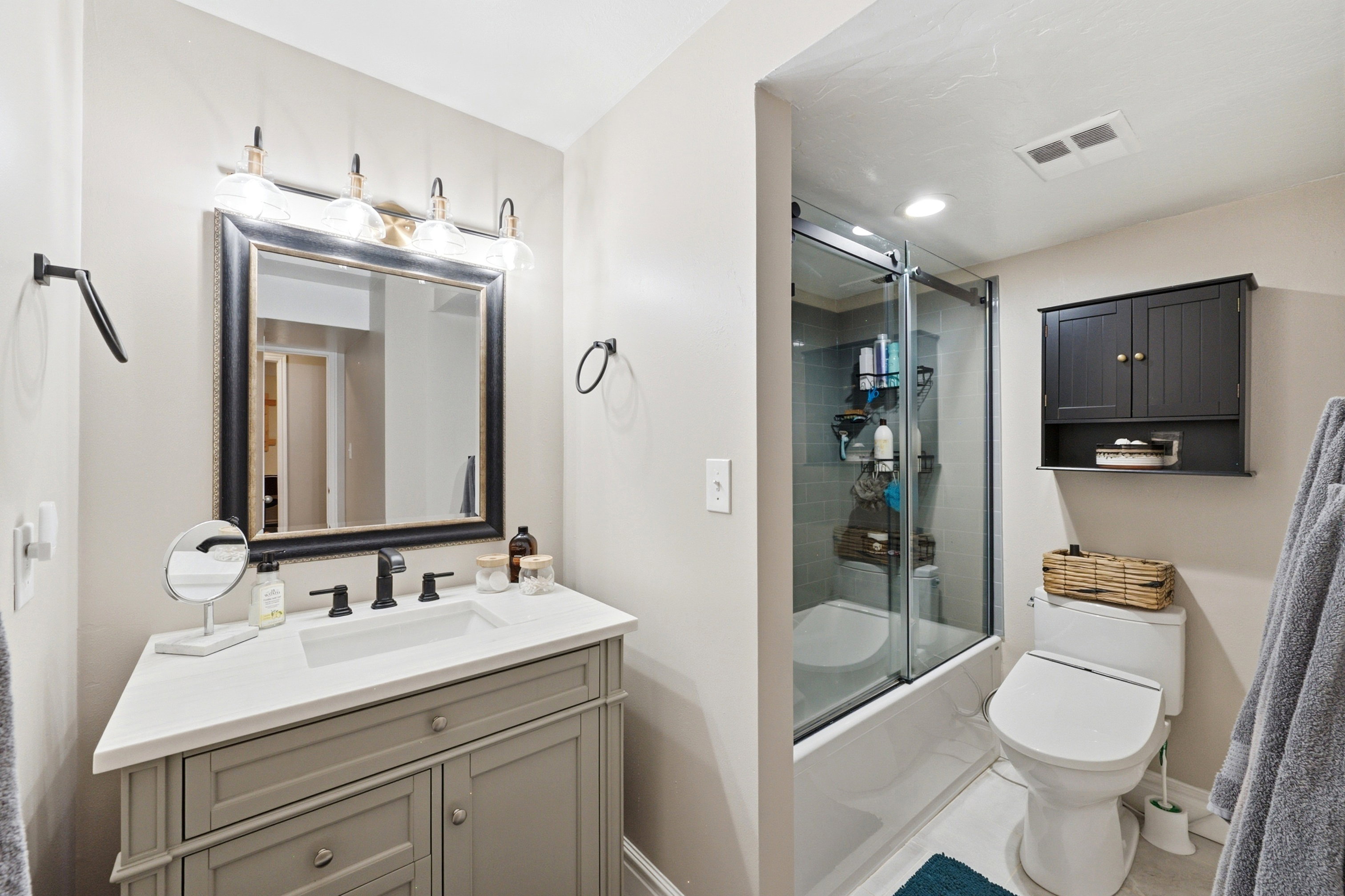 Bathroom featuring a single vanity with a light gray cabinet, white countertop, and integrated rectangular sink