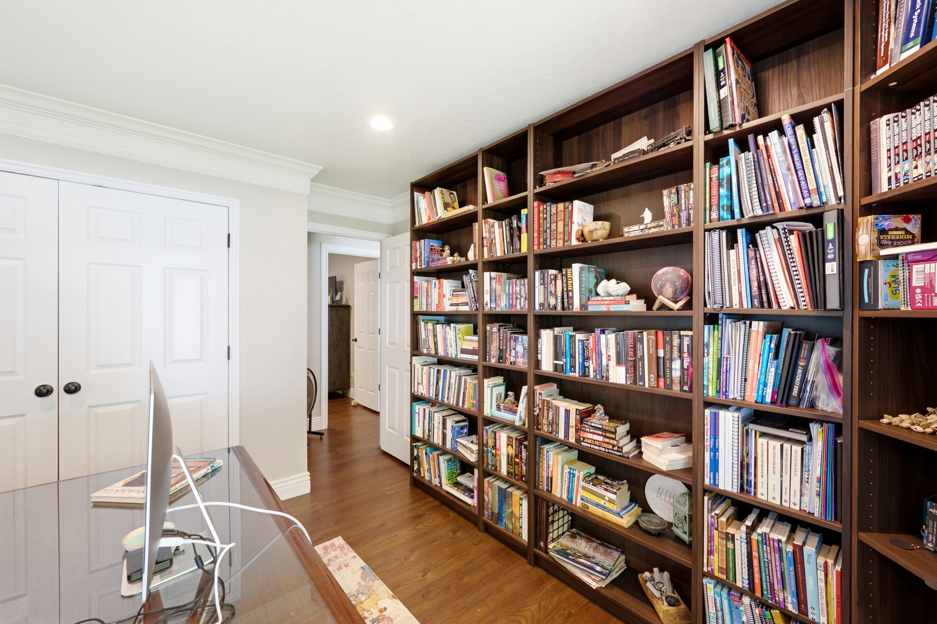 Integrated dark wood built-in shelving, recessed lighting, and wood-finish flooring