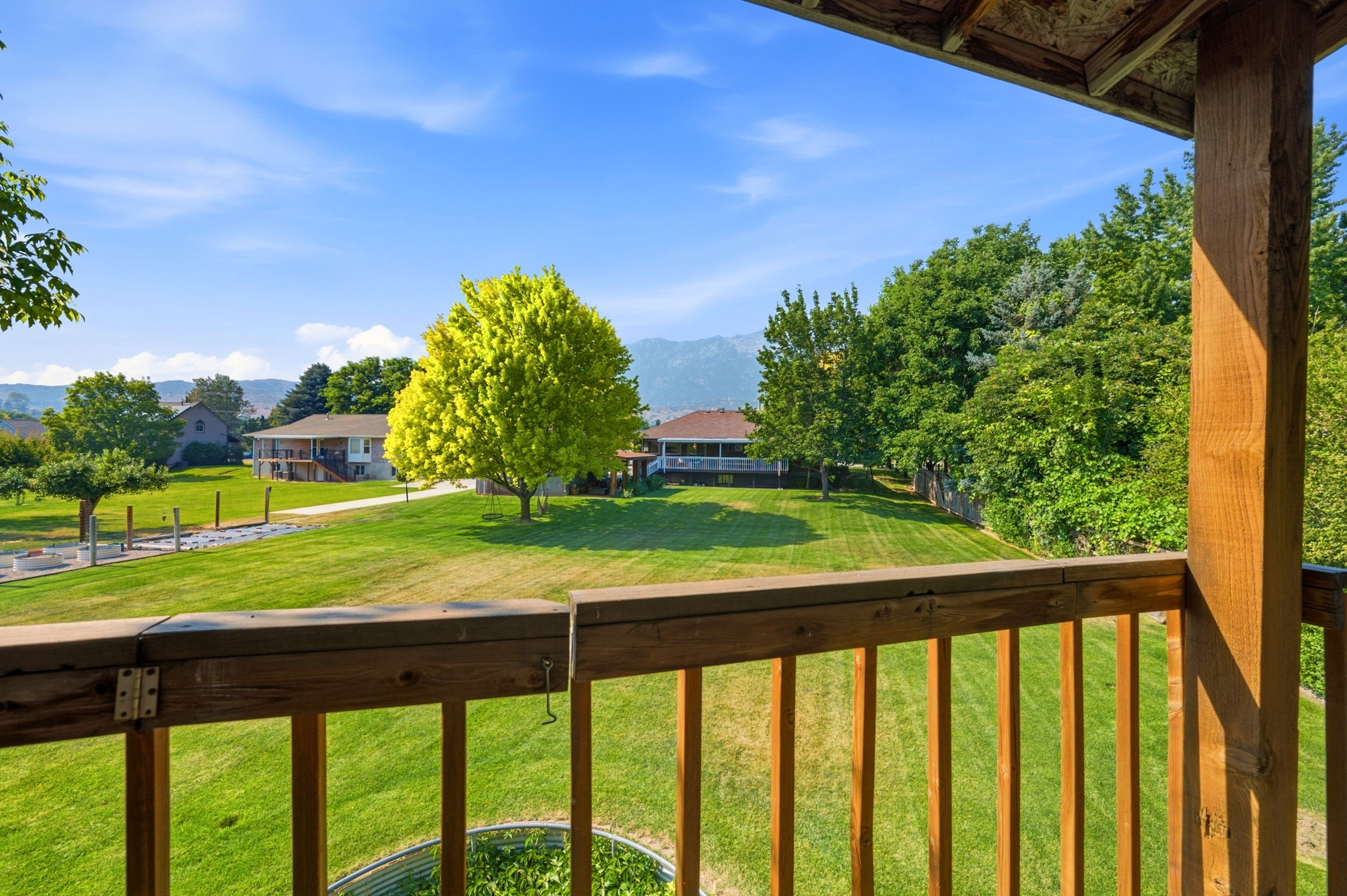 Expansive green lawn with mature trees and mountain backdrop