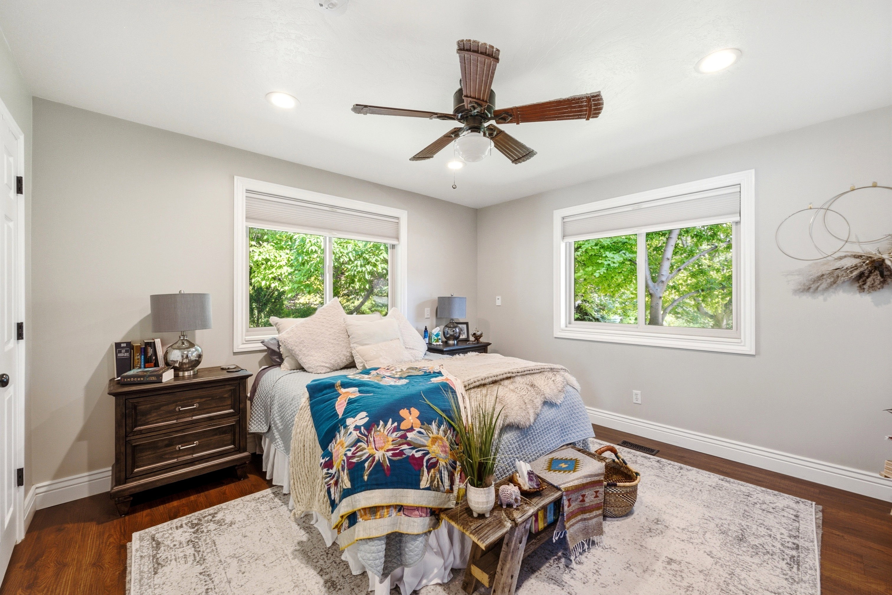 Bedroom featuring two large windows with white trim, wood-finish flooring, a ceiling fan with integrated lighting, and recessed ceiling lights