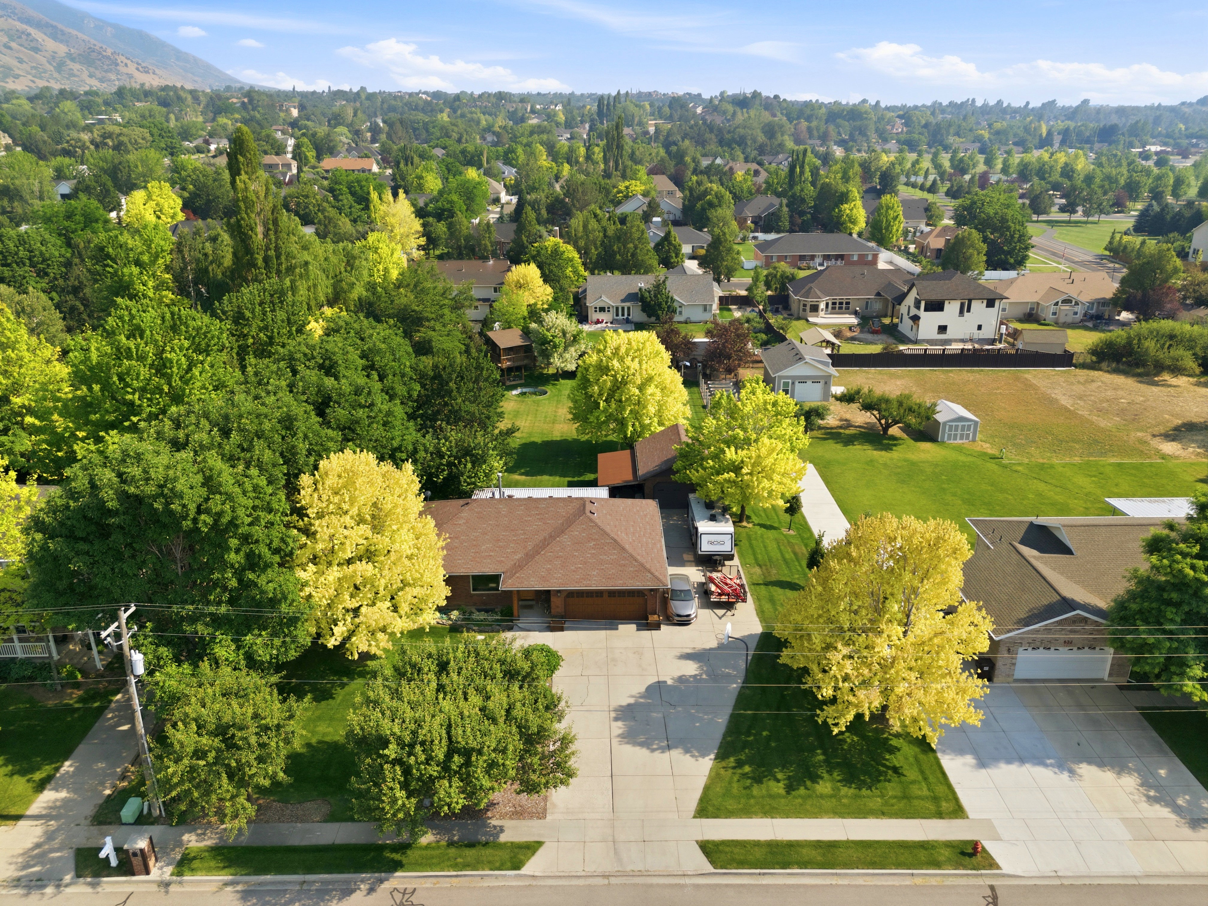 Brown single-story residence featuring a front-facing garage, a light brown shingle roof, and an asphalt driveway