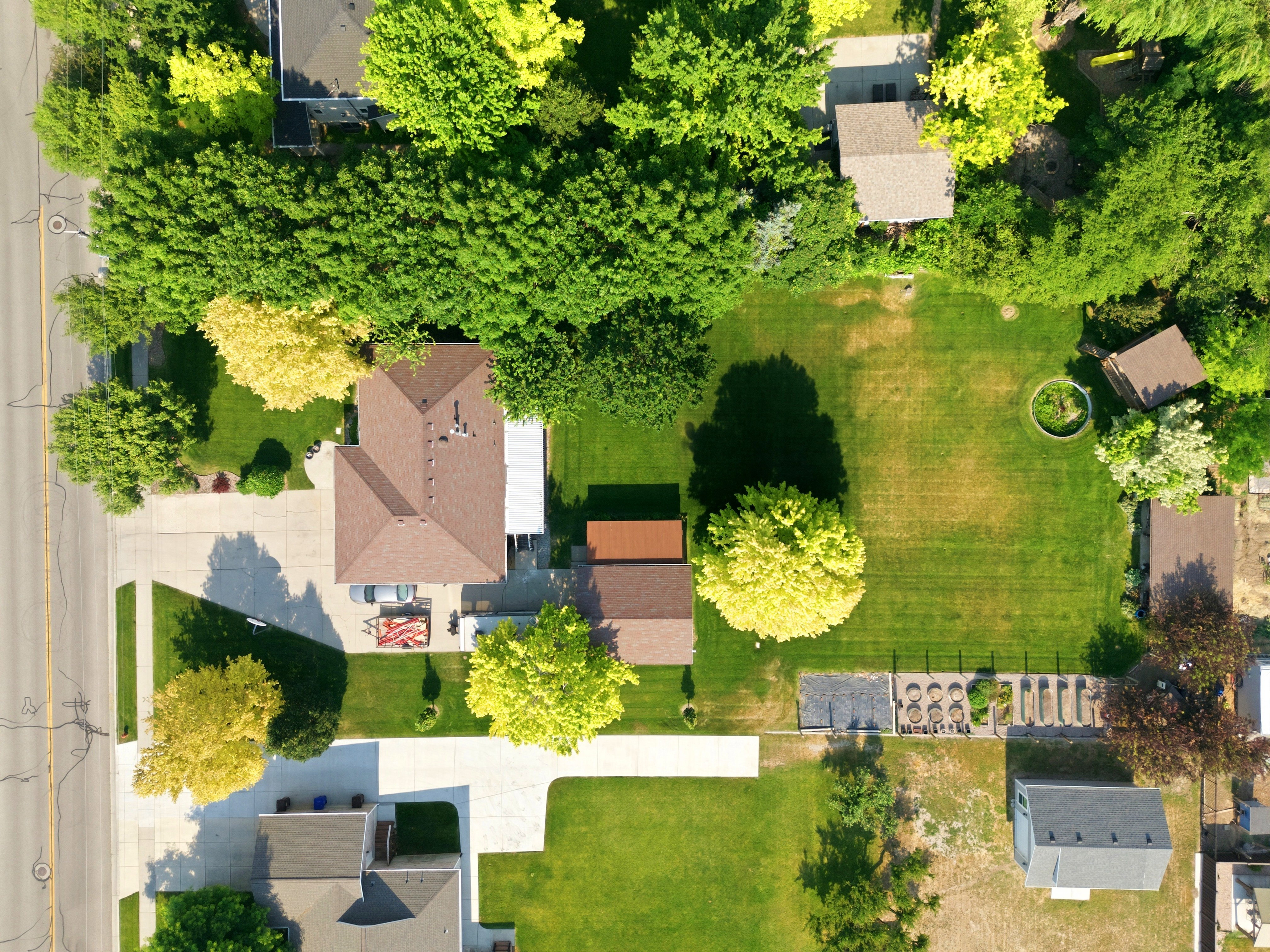 Spacious property featuring a large manicured lawn, mature trees, and a substantial driveway