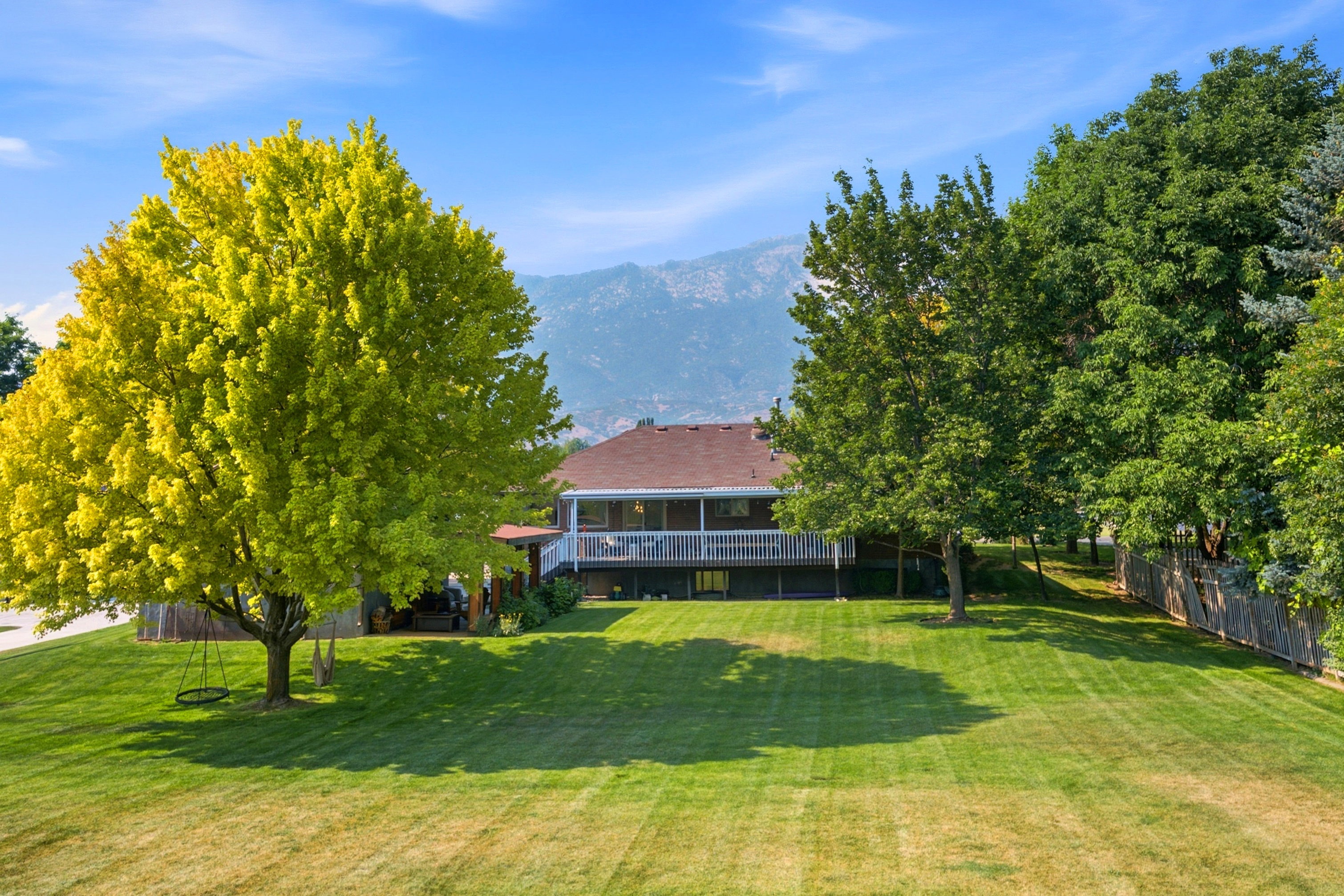 Expansive rear yard featuring a large manicured lawn and mature trees