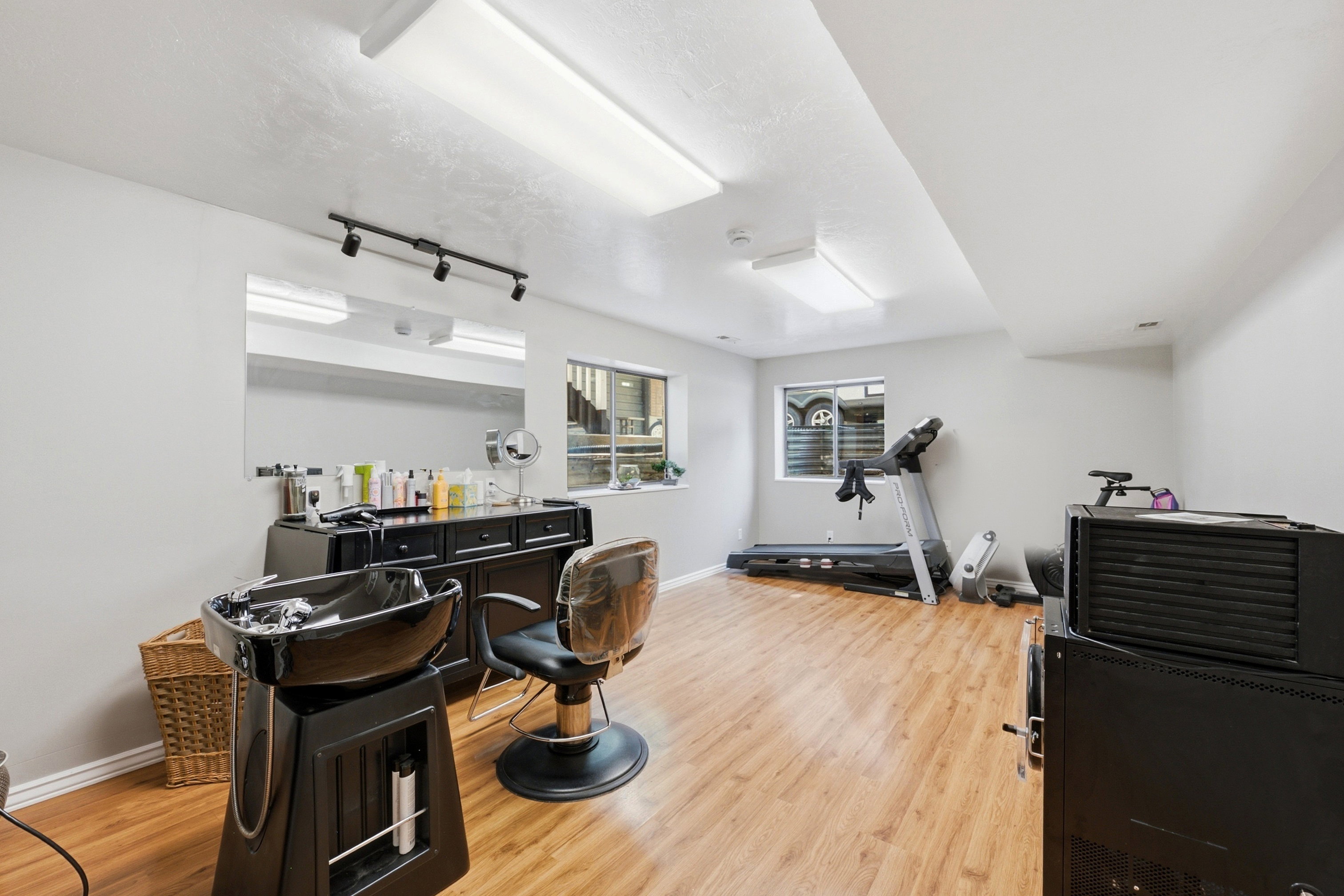 Spacious room featuring wood-finish flooring, light gray walls, and multiple windows