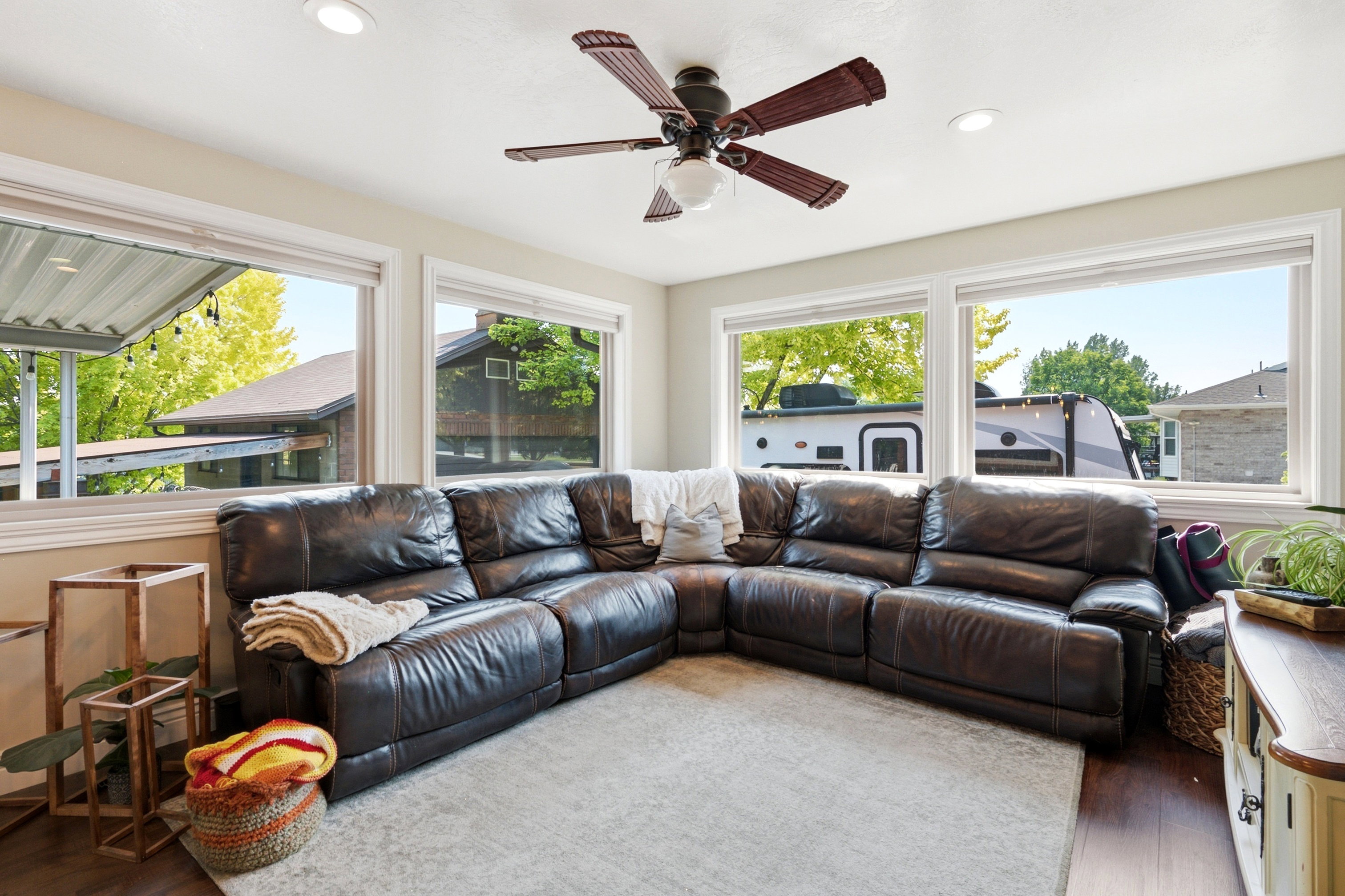 Bright room featuring multiple windows, a ceiling fan with integrated lighting, recessed lighting, wood-finish flooring, and a light-toned area rug
