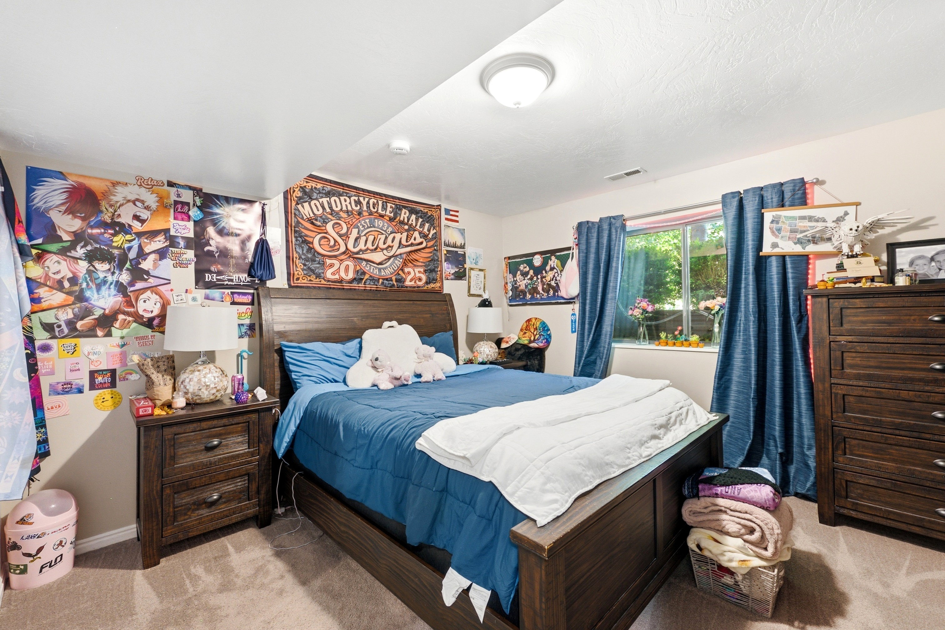 Carpeted bedroom featuring a window with blue curtains, a ceiling-mounted light fixture, and a built-in closet visible on the left