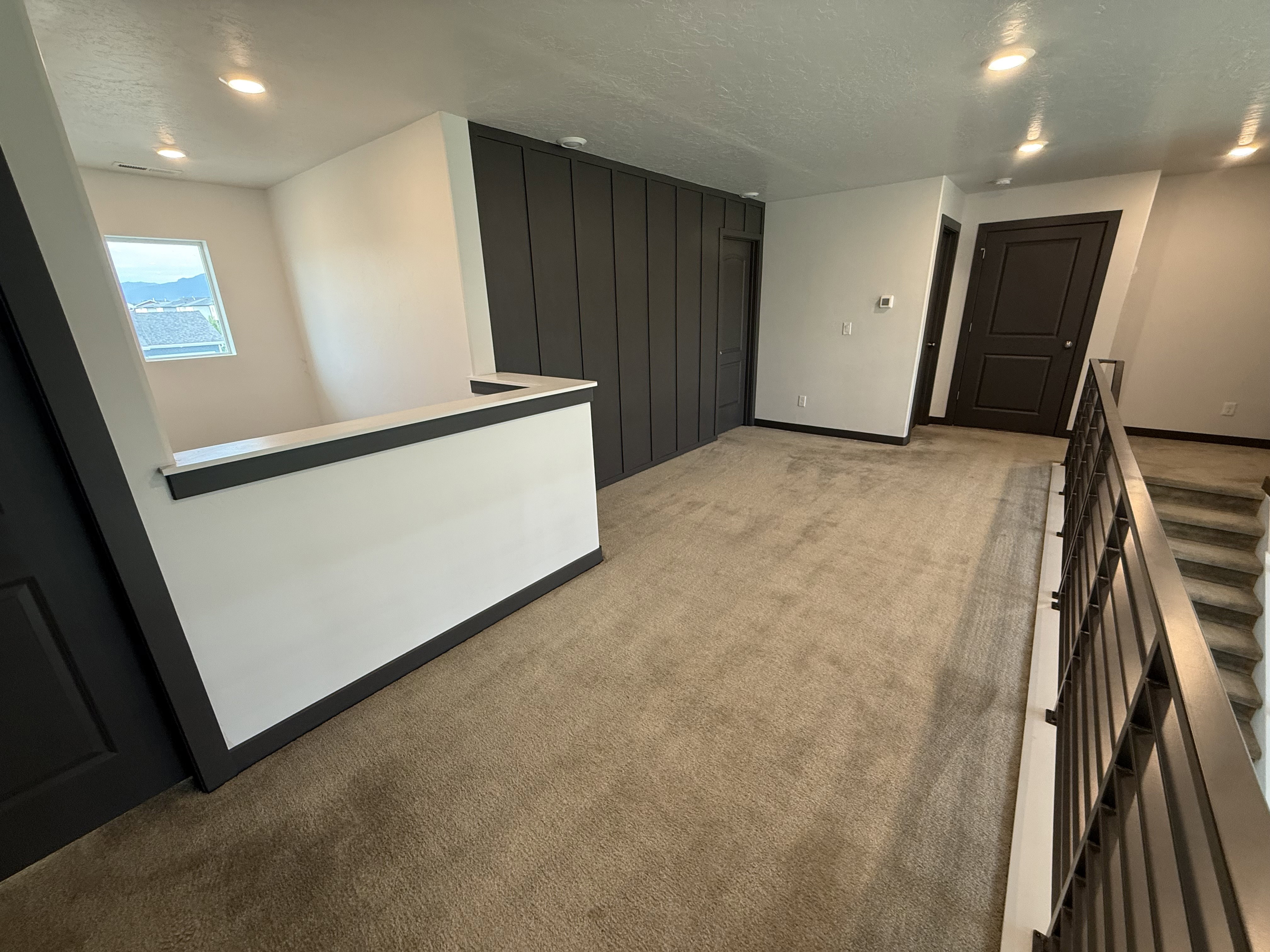 Carpeted hallway with a dark accent wall, recessed lighting, and modern doors