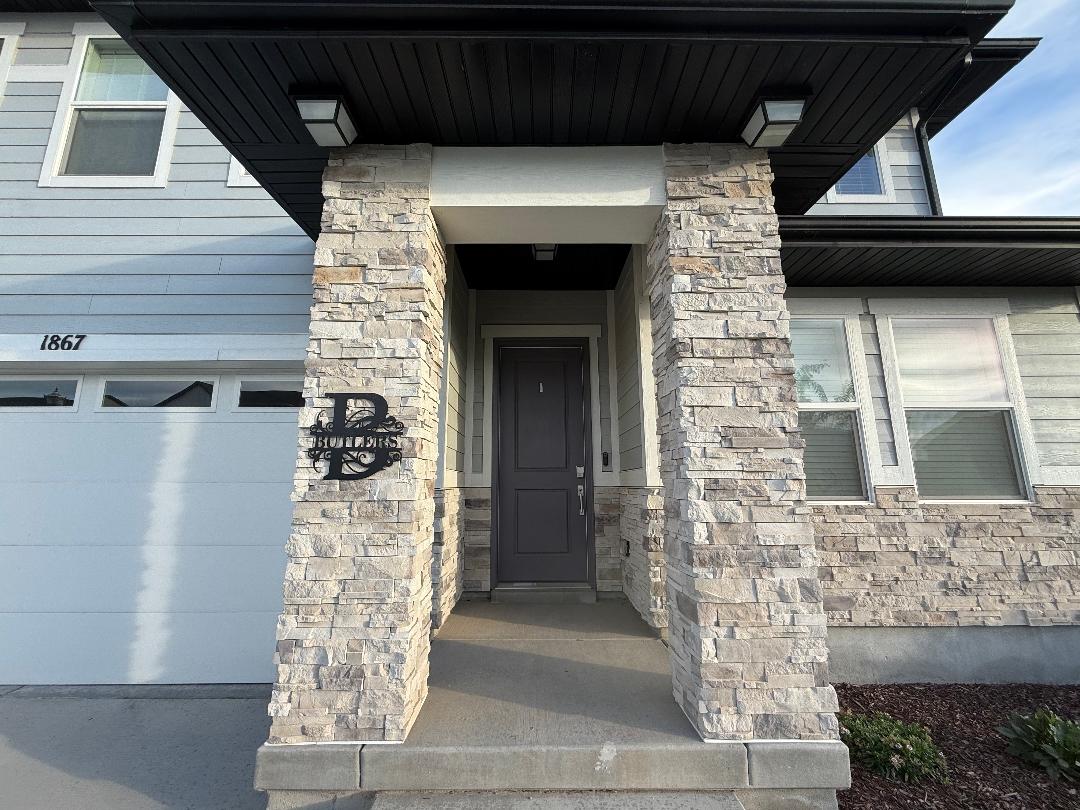 Stone veneer columns framing a covered entryway with a dark paneled door